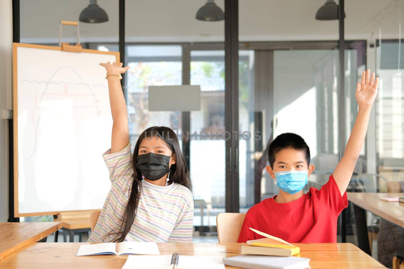 asian girl boy student wearing face mask studying raising hand in classroom. learning education at school