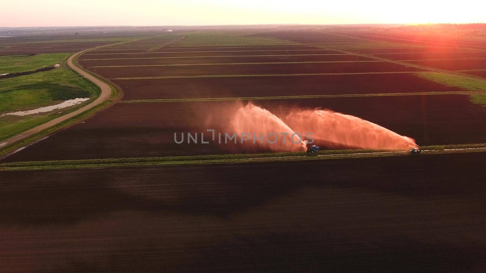 Irrigation equipment watering freshly seeded field.Irrigation at sunset.Irrigation of farmland to ensure the quality of the crop. Aerial view:irrigation system watering a farm field.