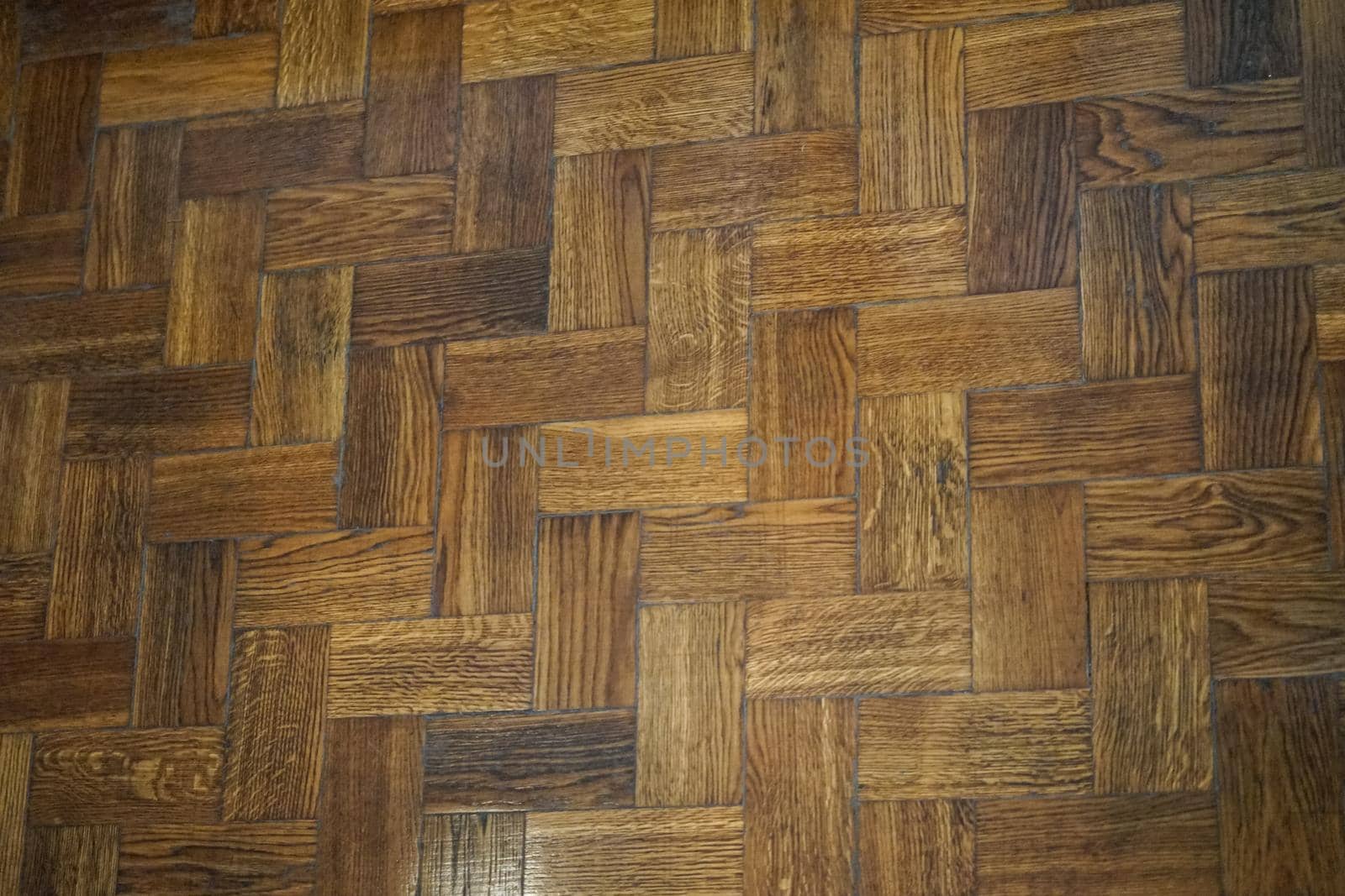 background of old wooden herringbone parquet flooring composed of boards of a different color.