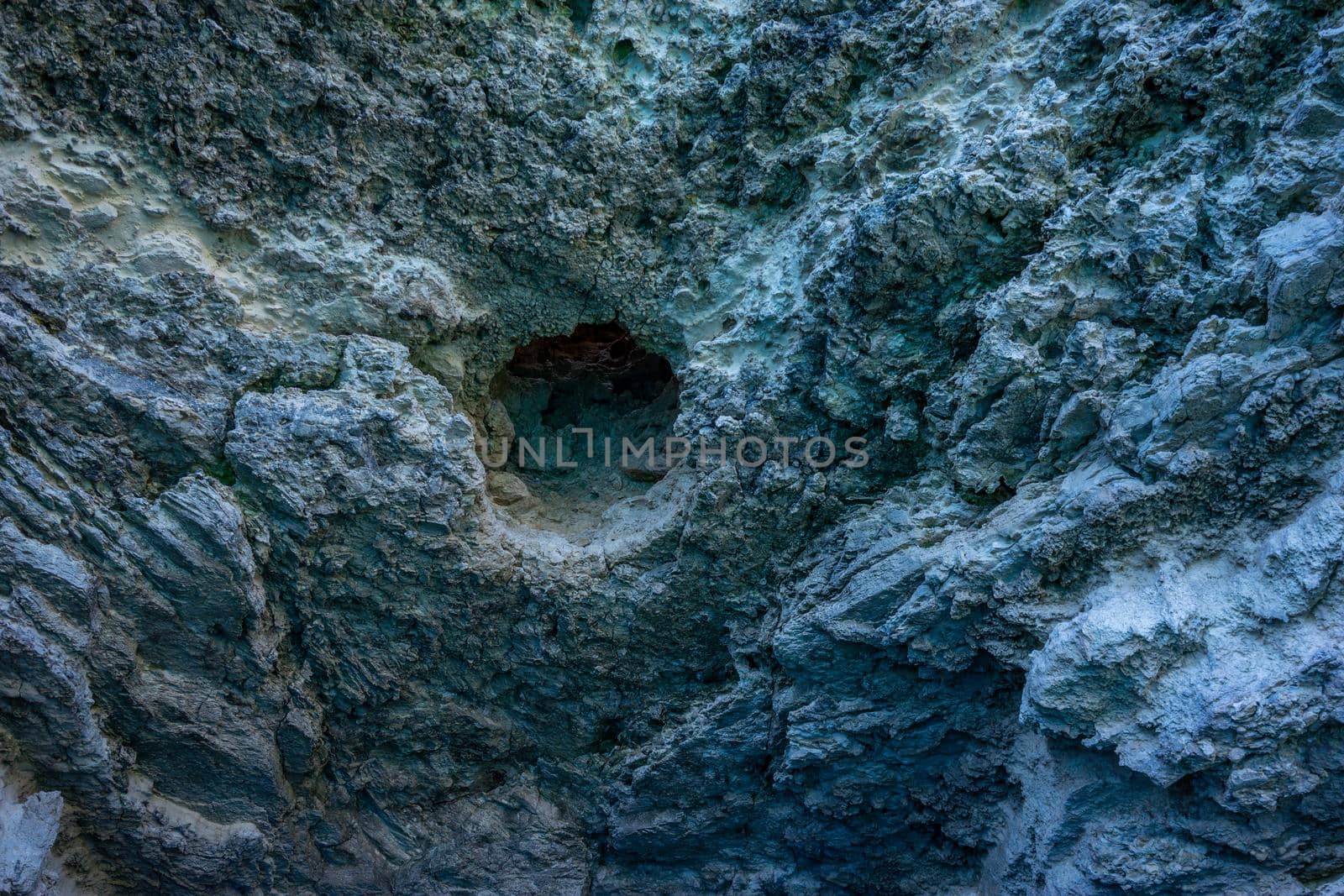 Background with a textured gray rock surface with a hole.