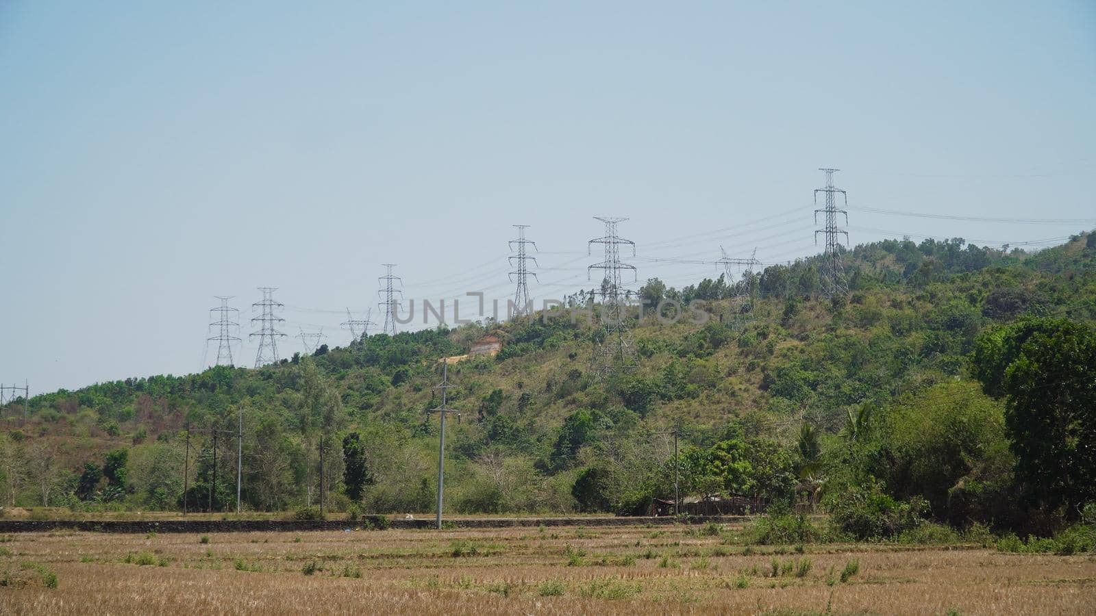 Power pylons and high voltage lines passing through mountain cordillera. Philippines, Luzon. High voltage metal post, tower. Electric Power Transmission Lines over trees.