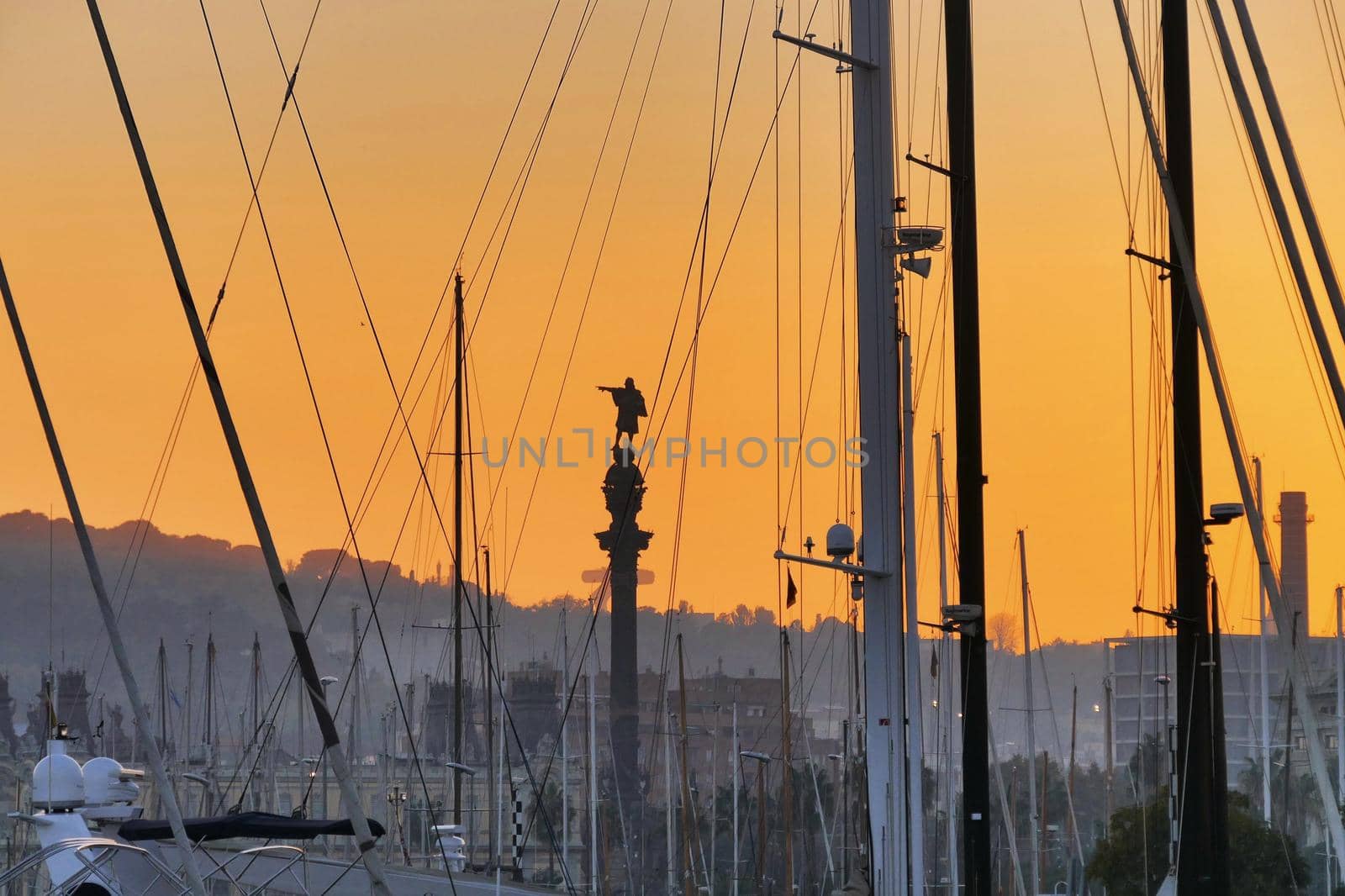 Cristoforo Colombo statue silhouette view through trees and shrouds of the boats moored in the port at sunset by lemar