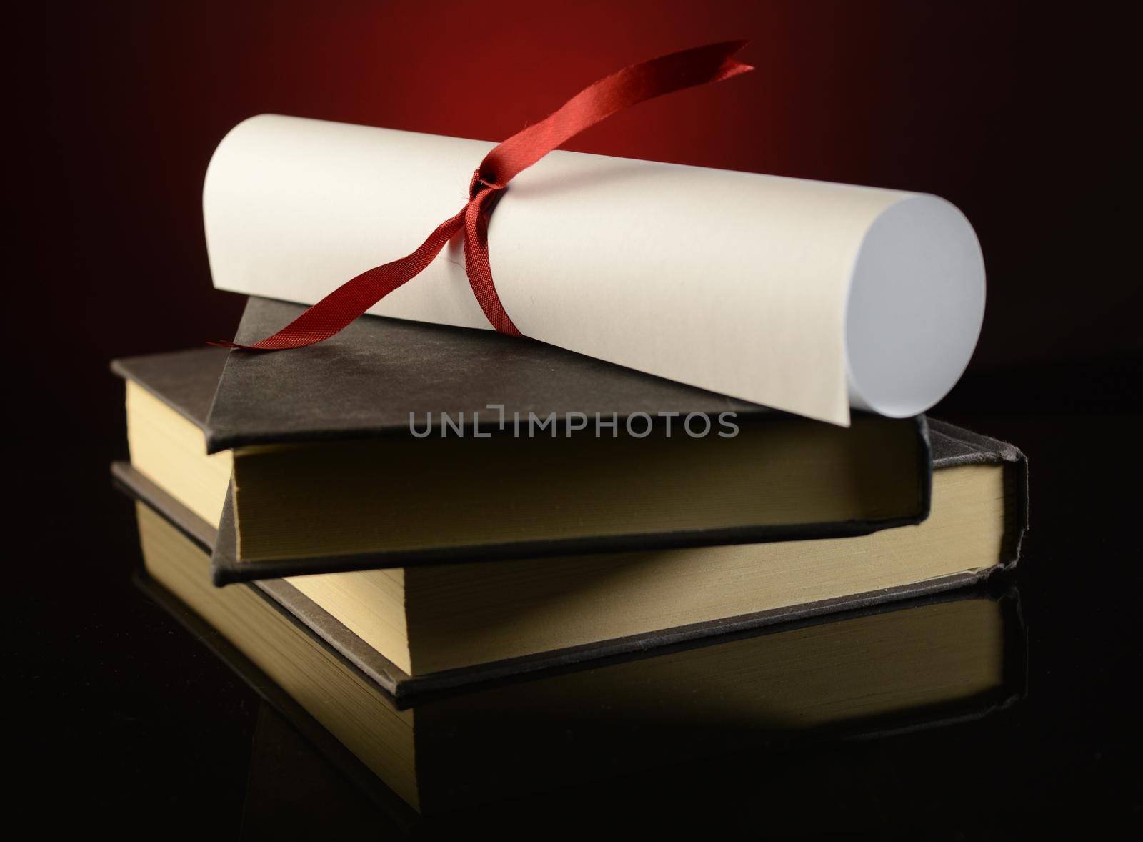 A diploma on top of a couple books shows the successful payoff of school studies.