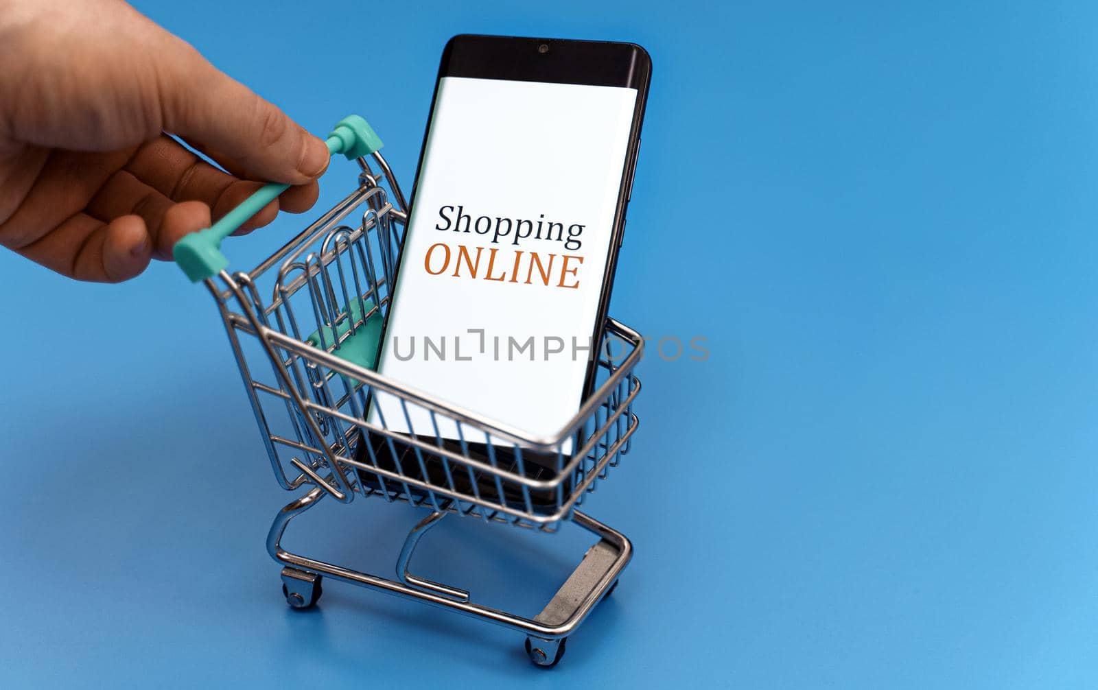 Shopping cart with smartphone on blue background. Online shopping concept. by dmitrimaruta