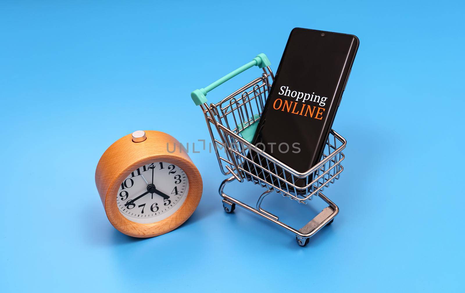 Shopping cart with smartphone and clock. Online shopping concept. by dmitrimaruta