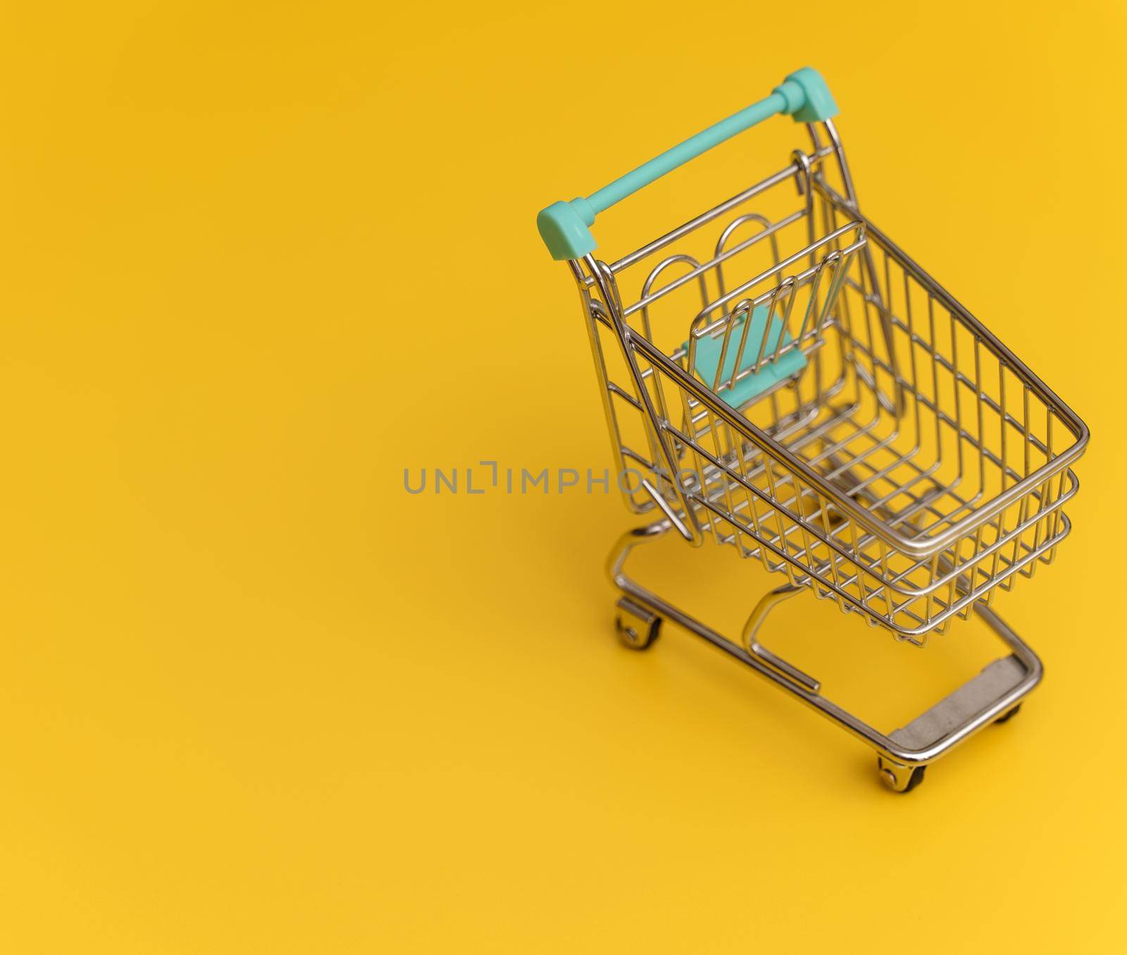 Empty shopping cart on yellow background. by dmitrimaruta