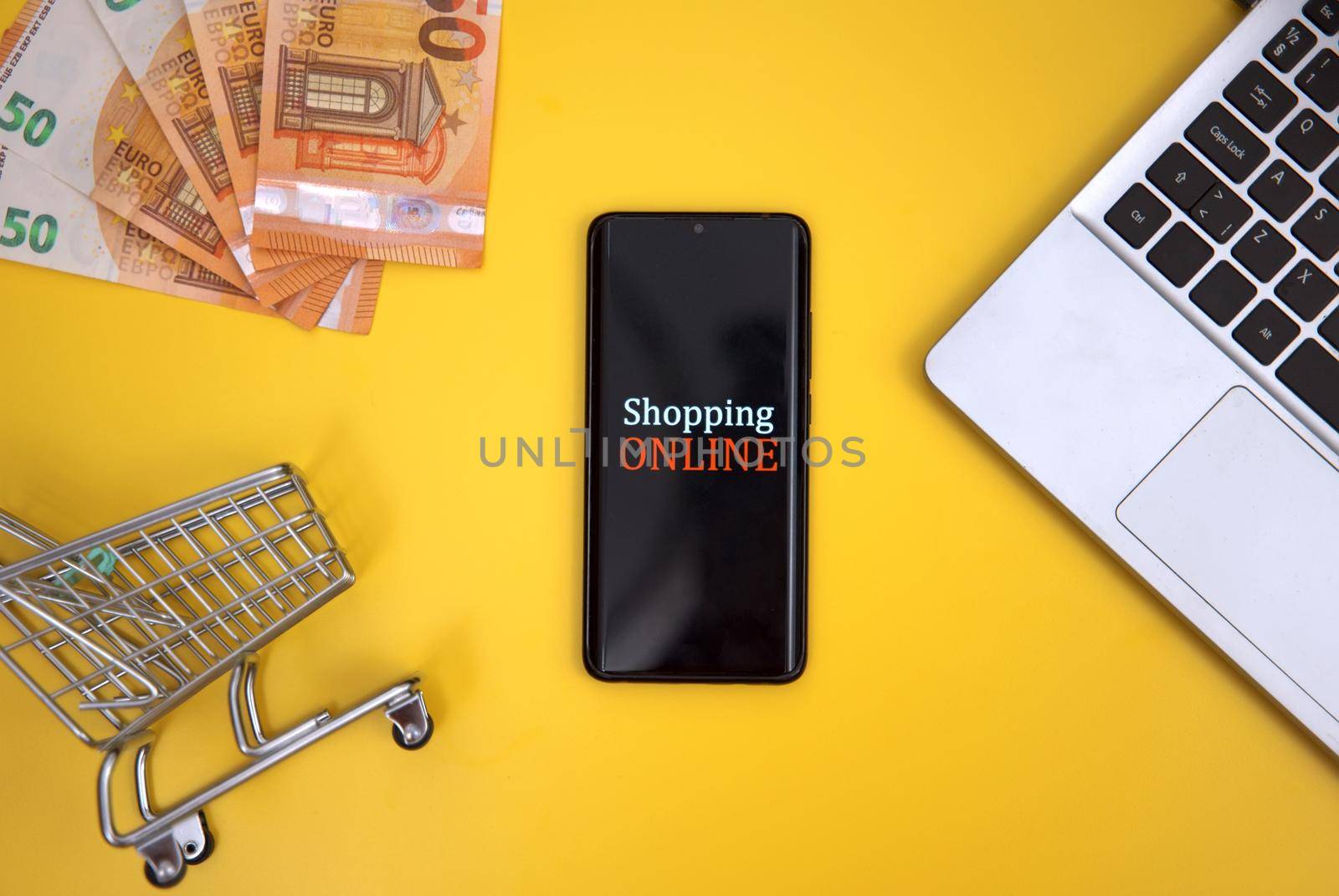 Mobile phone, shopping cart and money. Online shopping concept.