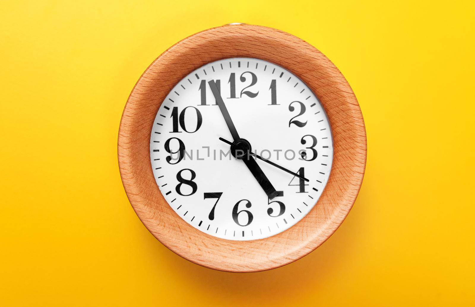 Wooden round clock on yellow background. by dmitrimaruta