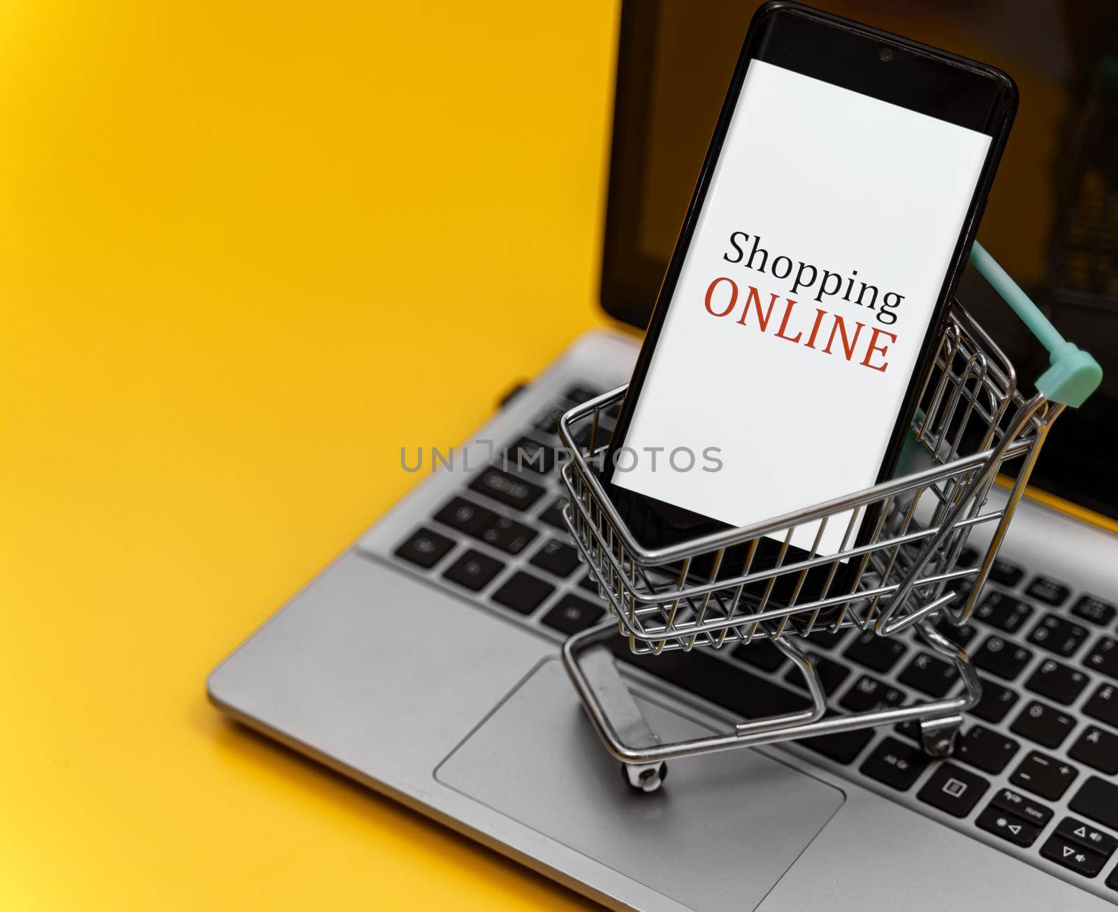 Shopping cart with smartphone on notebook. Online shopping concept. by dmitrimaruta