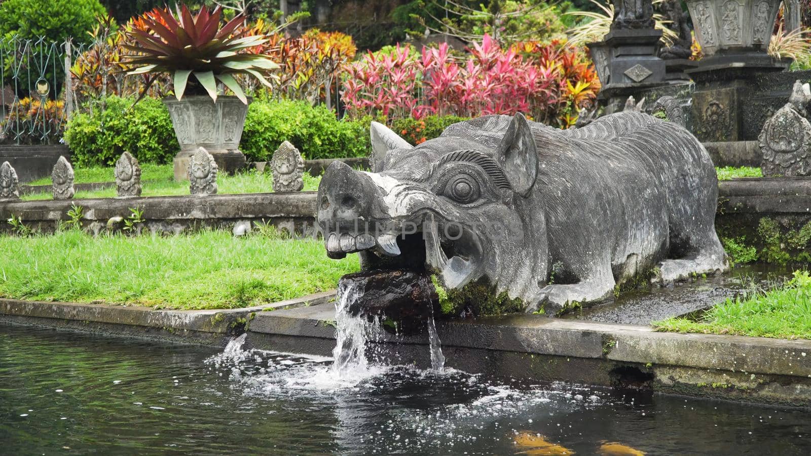 Hindu Balinese Water Palace Tirta Gangga with statues of the gods, fountains in the form of a wild boar on Bali island, Indonesia. Tirta Gangga the former royal water palace is a maze of pools and fountains surrounded by a lush garden and stone carvings and statues.