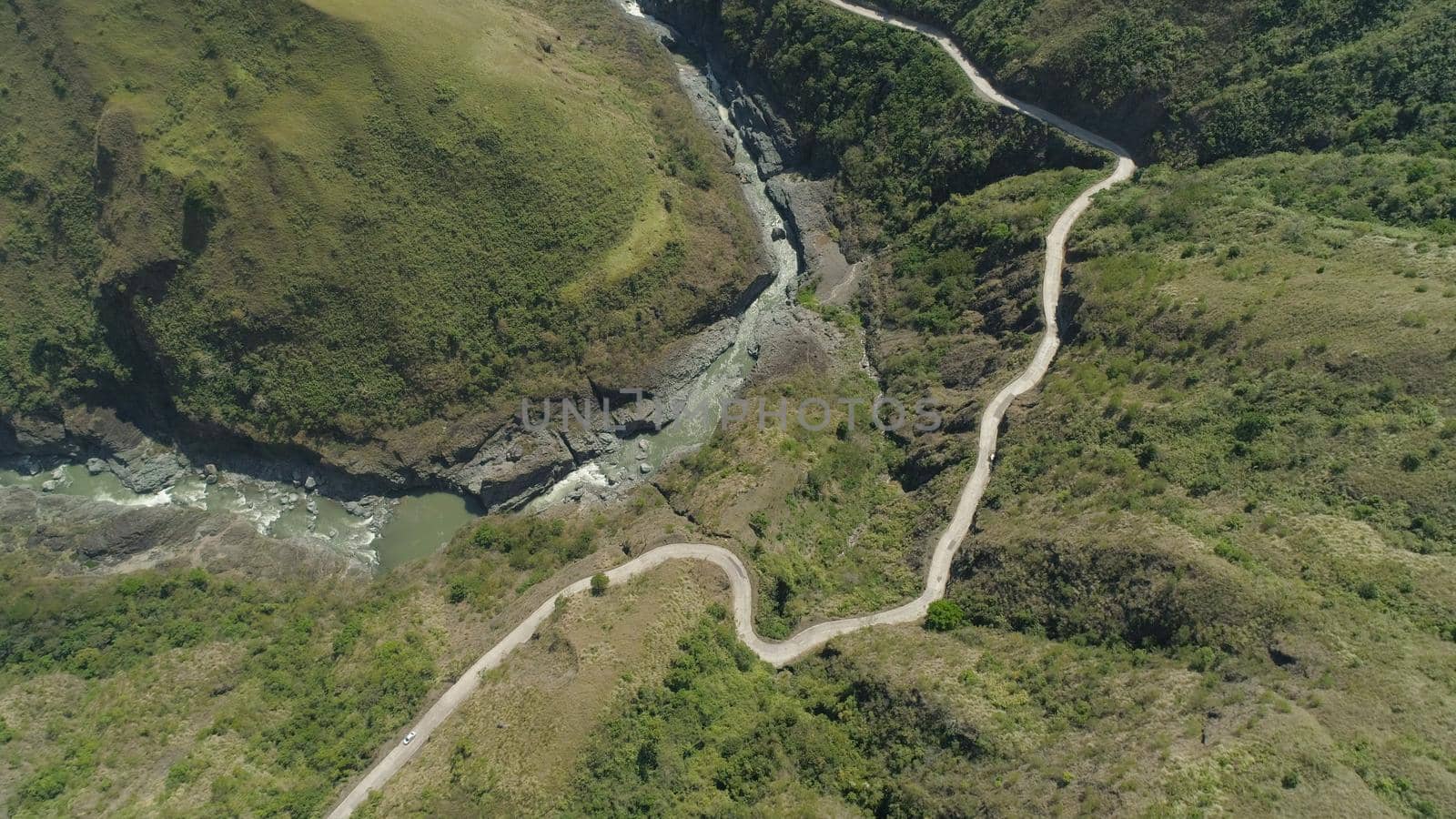 Aerial view of mountain river in the cordillera, road on the slopes, mountains covered forest, trees. Cordillera region. Luzon, Philippines.