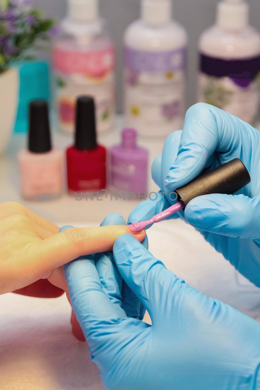 In a beauty salon, a woman is given a manicure, a nail is painted with varnish. Close-up.