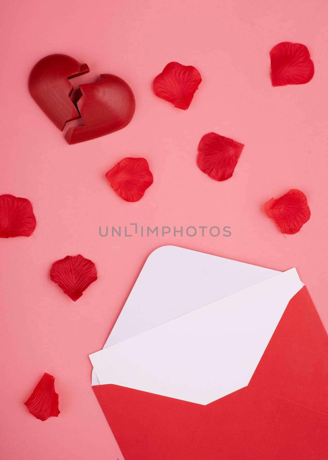 open envelope with blank, broken heart and rose petals on pink background