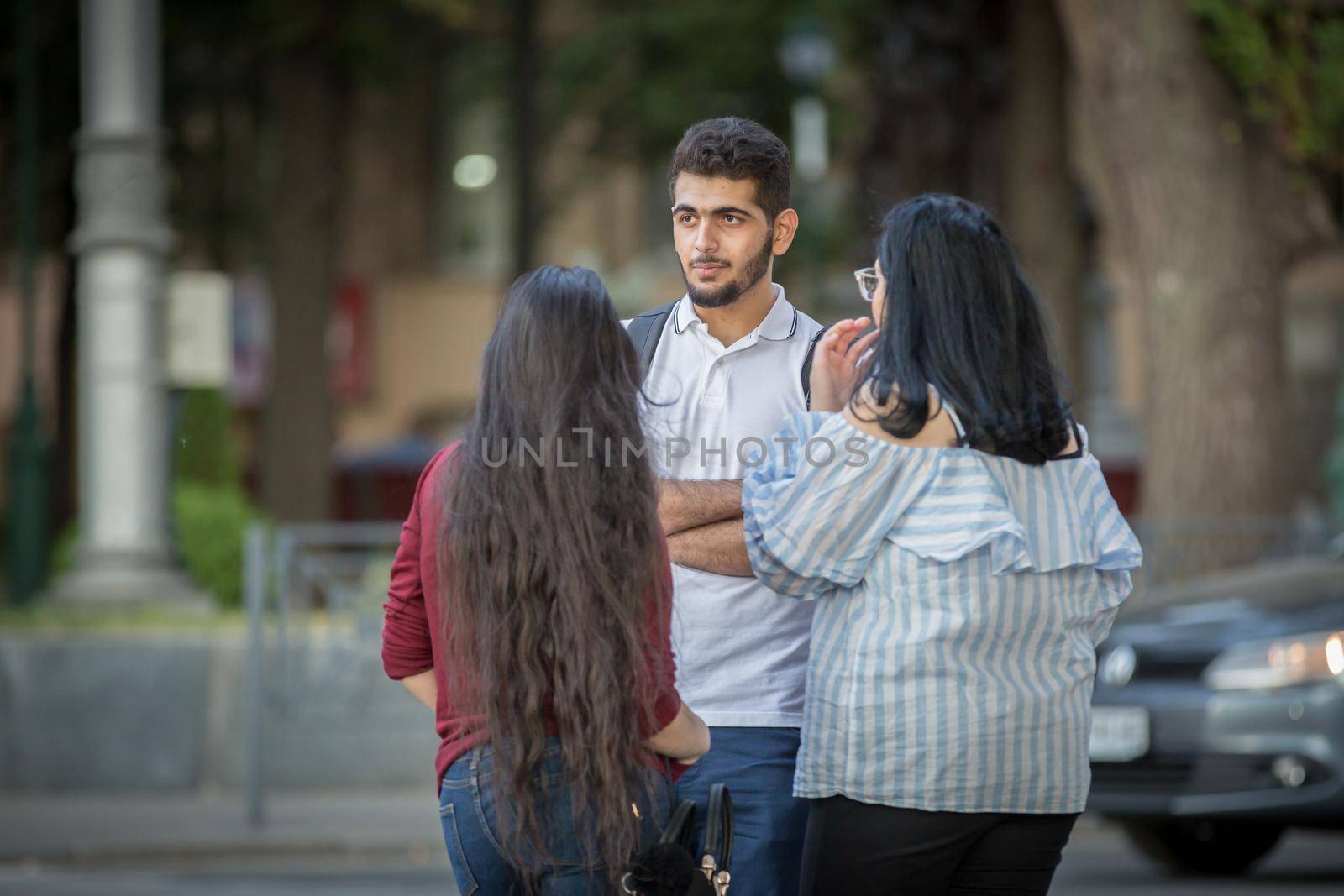 Foreign students. Friends meeting on the street of a European city. A young man of oriental appearance is talking to girls. Students in a European city.