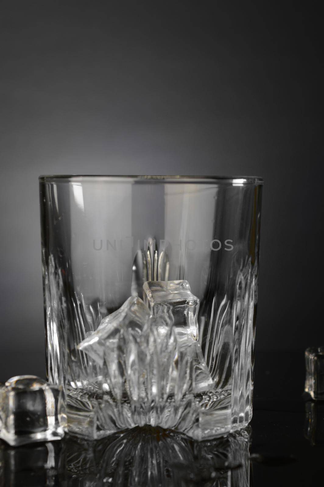A crystal whiskey glass with some fresh ice is being prepared on the counter.