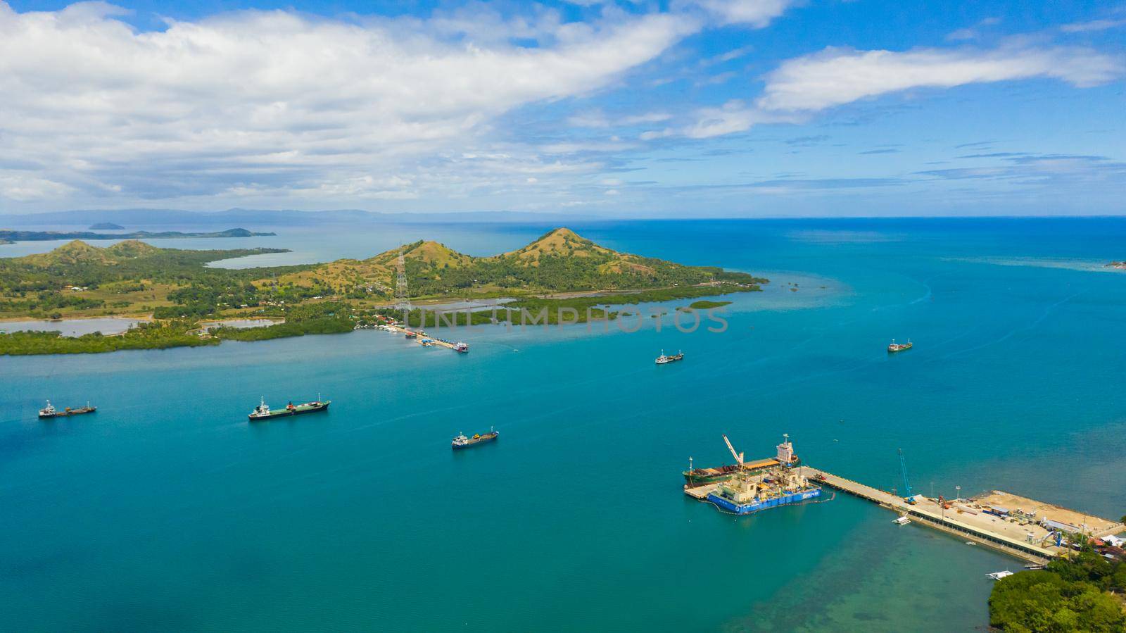 Aerial view of cargo ships leaving sea harbour at sunny day, islands on background. Tapal Wharf, Bohol, Philippines.