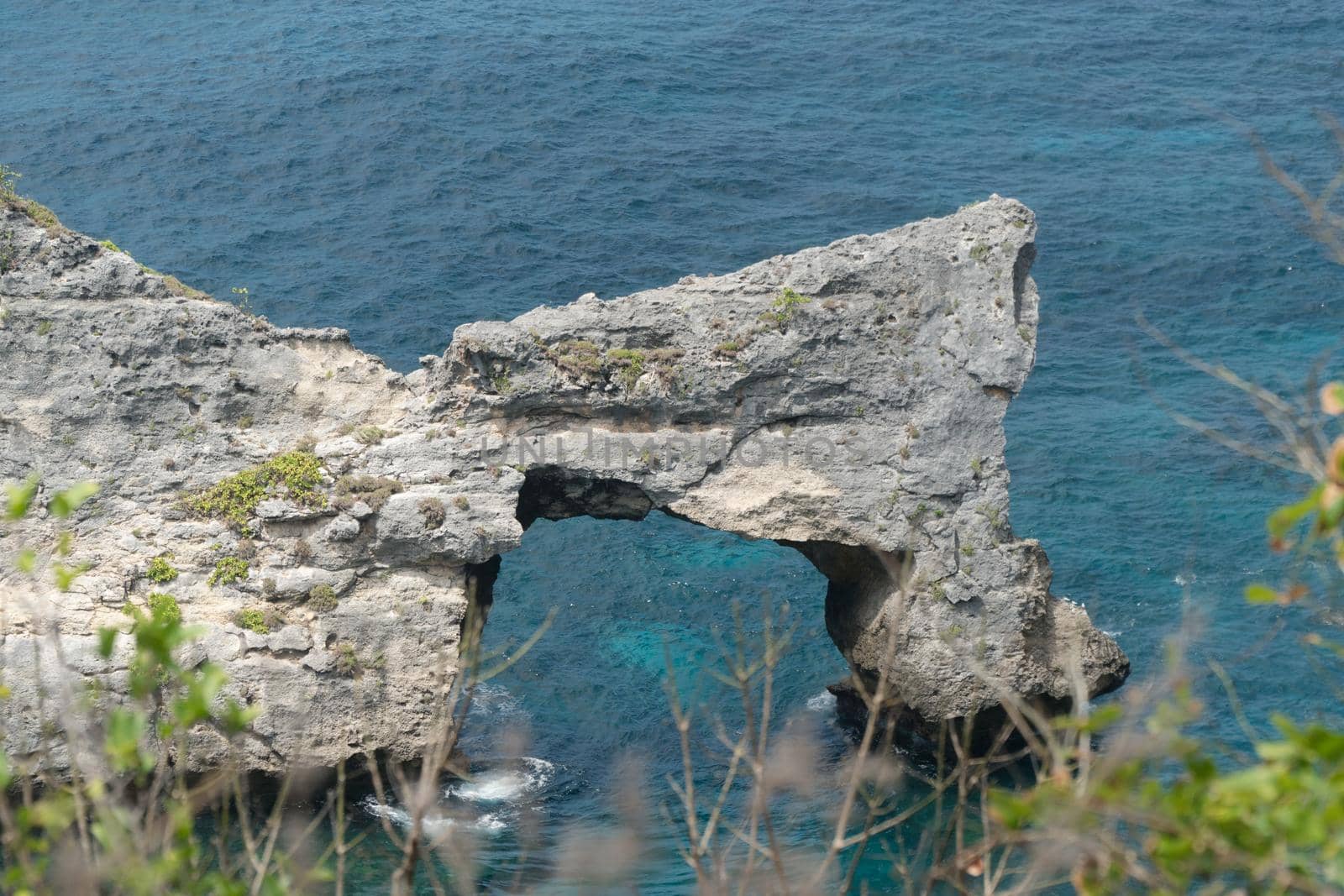 Rock in the ocean at Atuh beach on Nusa Penida island, Indonesia. Rocks in a blue sea lagoon with breaking waves. Travel concept