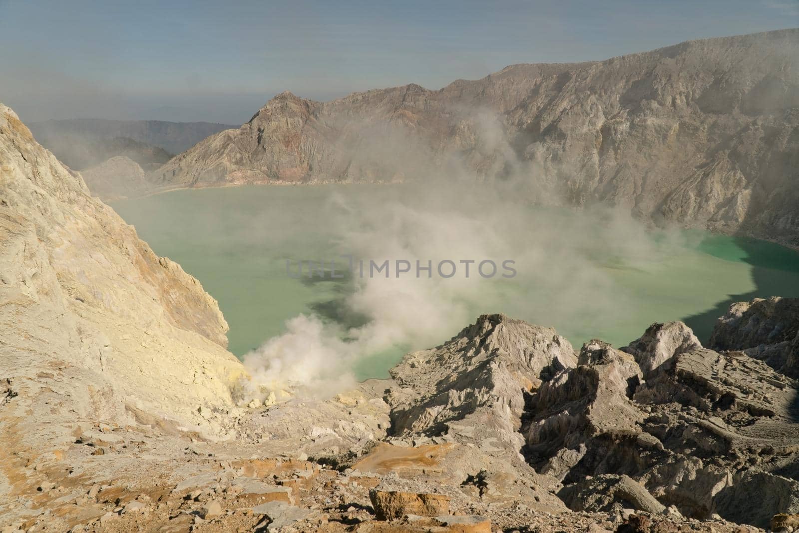 Crater with acidic crater lake, Kawah Ijen the famous tourist attraction, where sulfur is mined. Extraction of sulfur in the crater of a volcano. Sulfur gas, smoke.