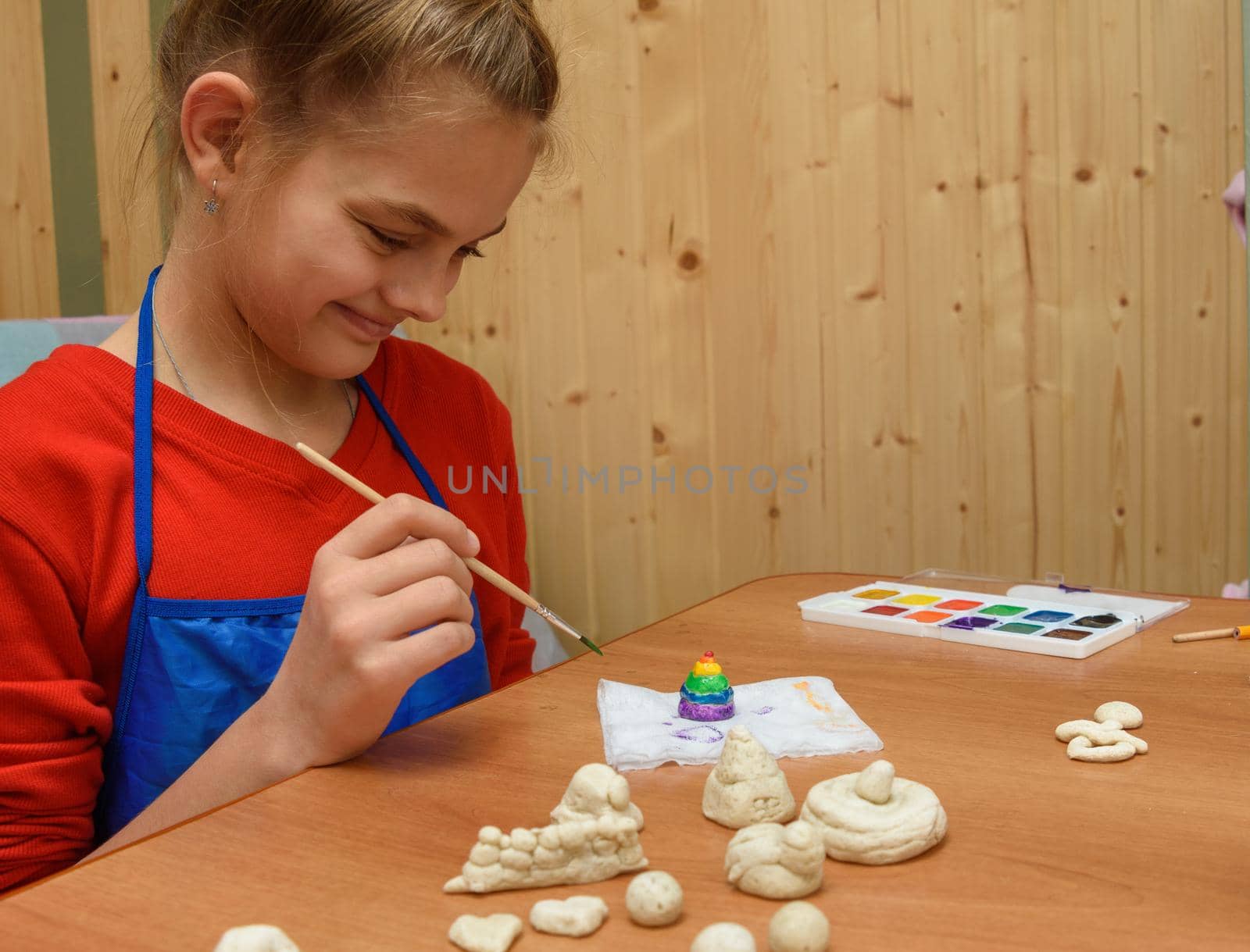 Girl rejoices at the finished painted figurine made of salt dough
