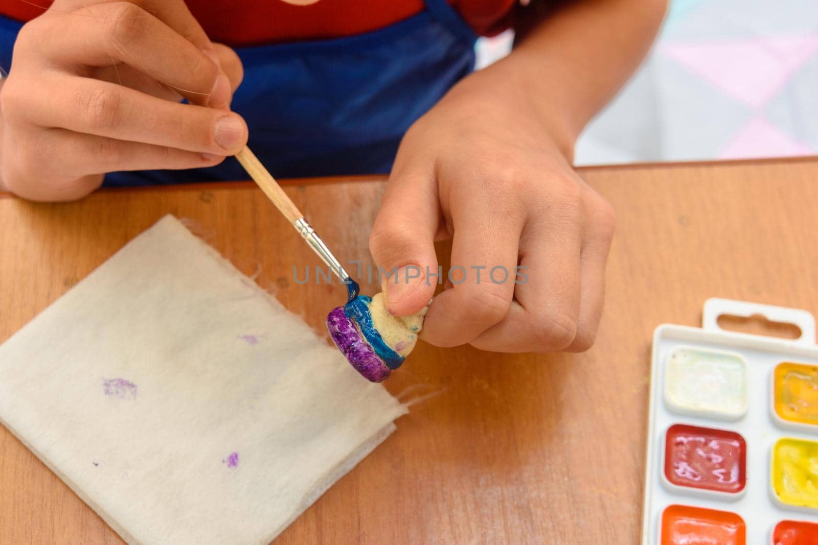 A girl paints a figurine made of salt dough with a brush