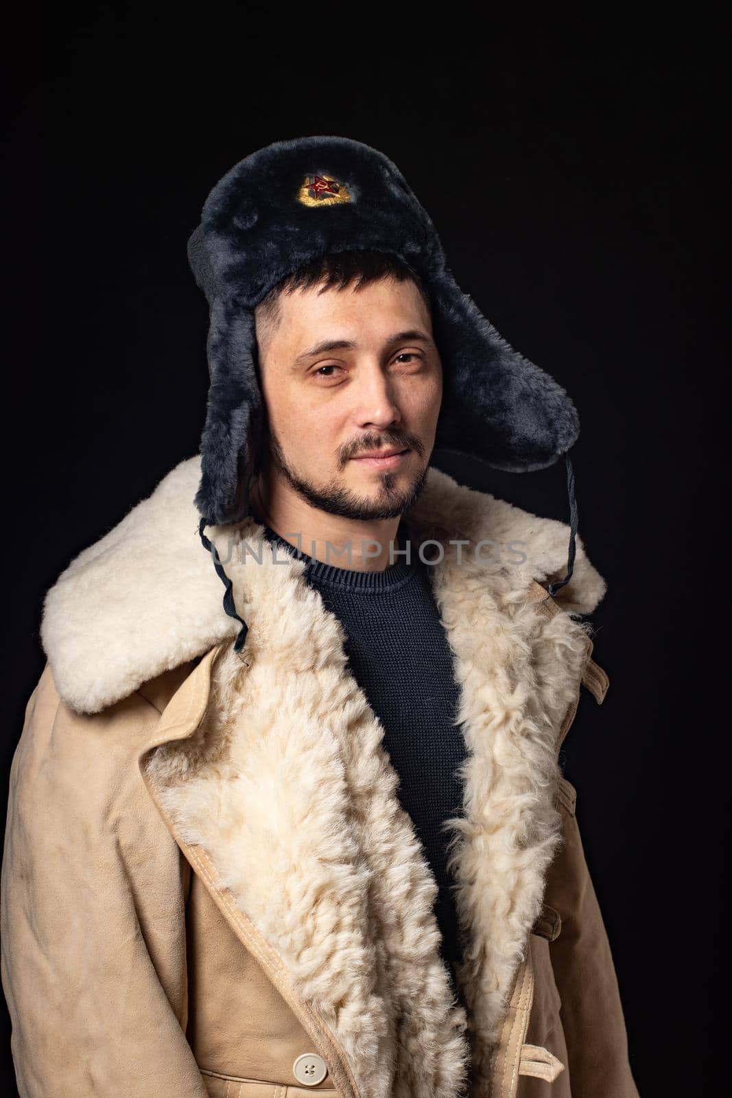 Portrait of a man of thirty years of Caucasian appearance in a Soviet officer's fur hat and an army sheepskin coat