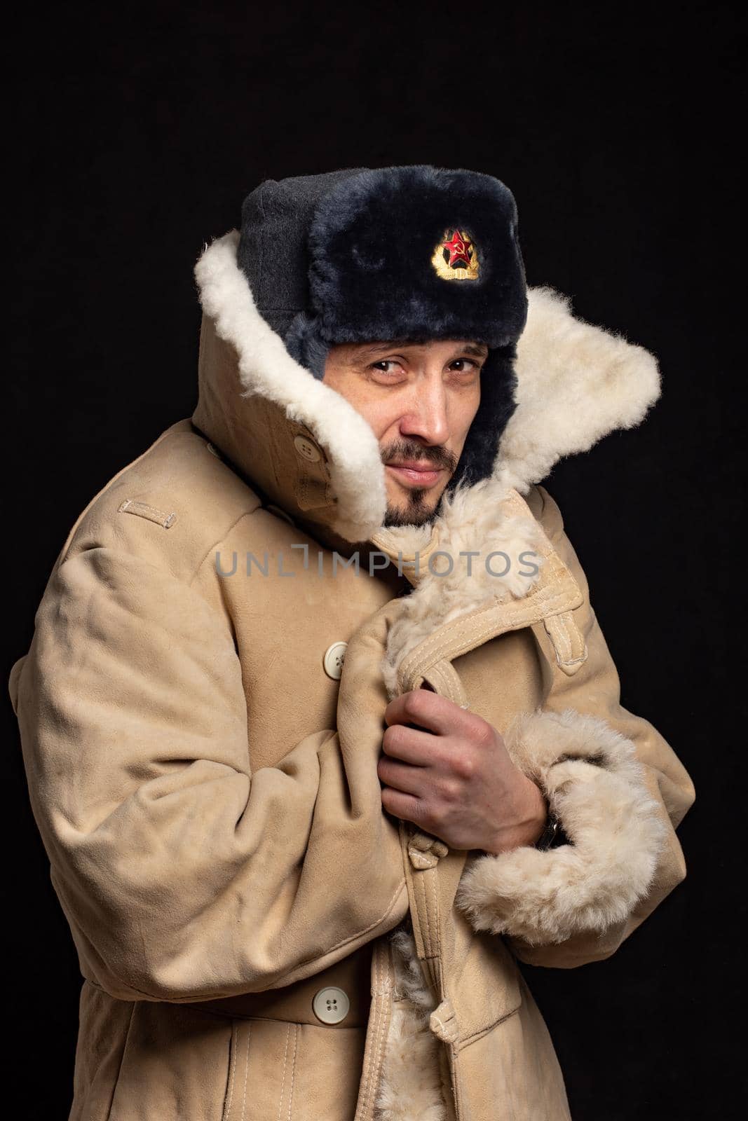 Portrait of a frozen man of Caucasian appearance in a Soviet officer's fur hat and an army sheepskin coat