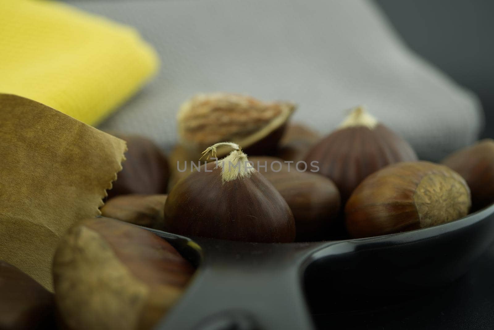 Fresh chestnuts also called sweet chestnut, Castanea sativa, Spanish chestnut in a black pan, low angle view and shallow focus