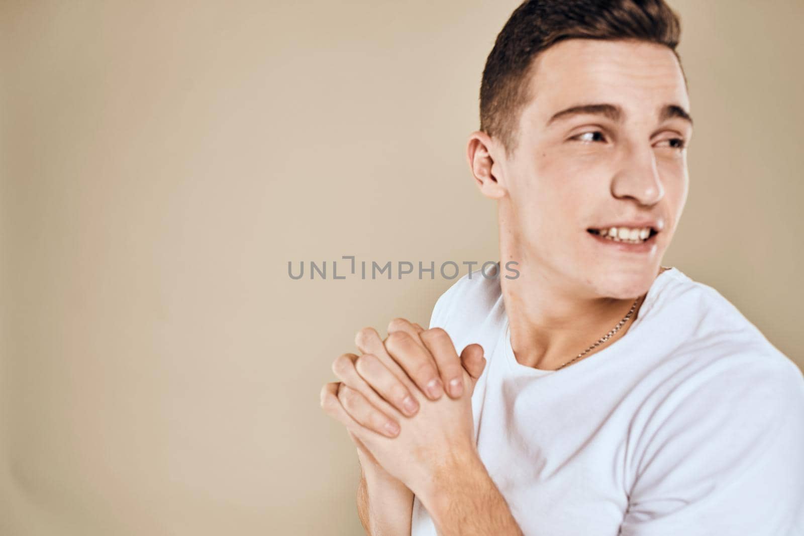 Emotional man white t-shirt gestures with hands lifestyle beige background. High quality photo