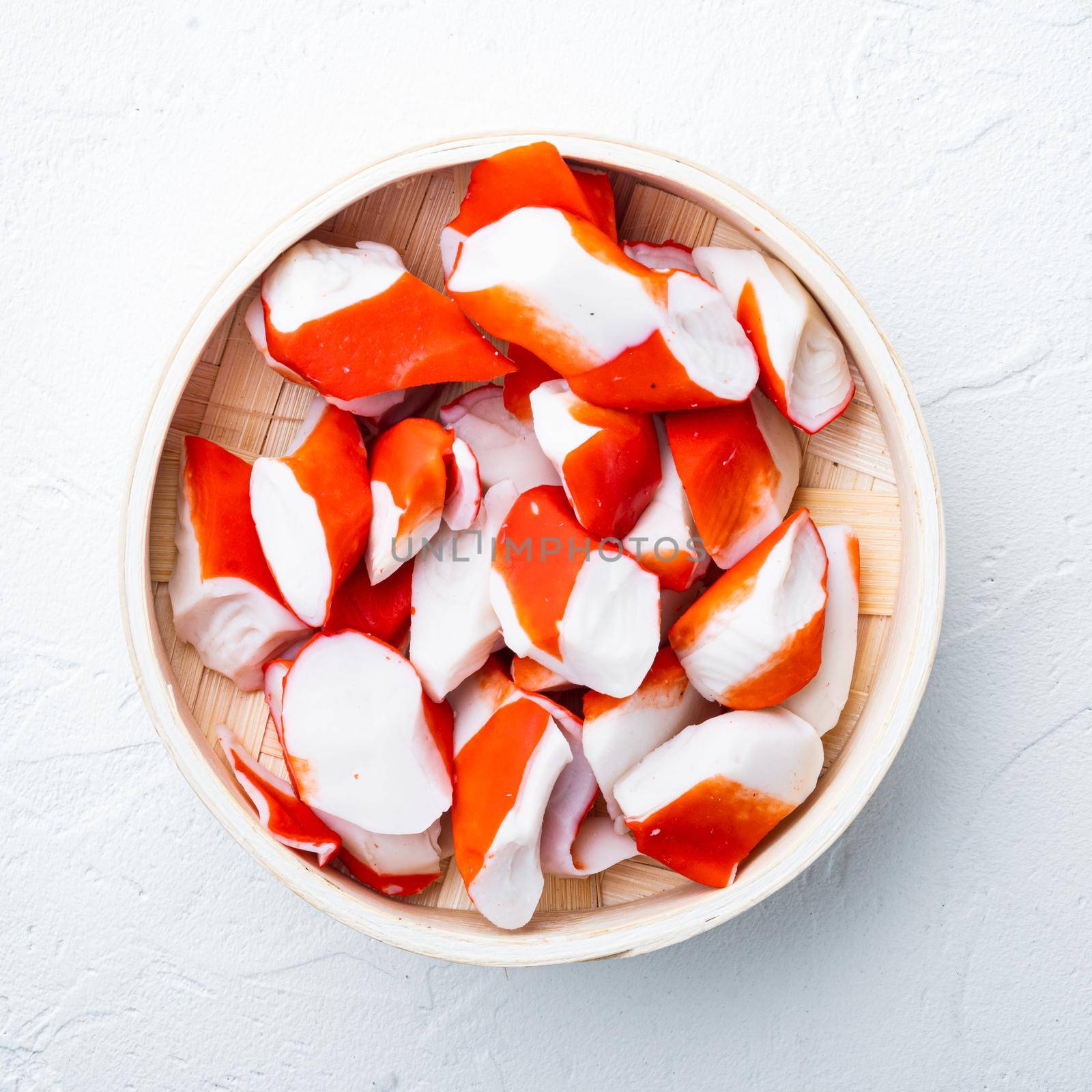 Fresh Crab meat stick surimi , on wooden tray, on white background, top view flat lay by Ilianesolenyi