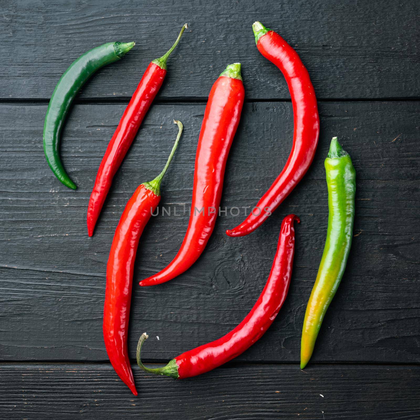 Ripe Red and green chili pepper, on black wooden table background, top view flat lay by Ilianesolenyi