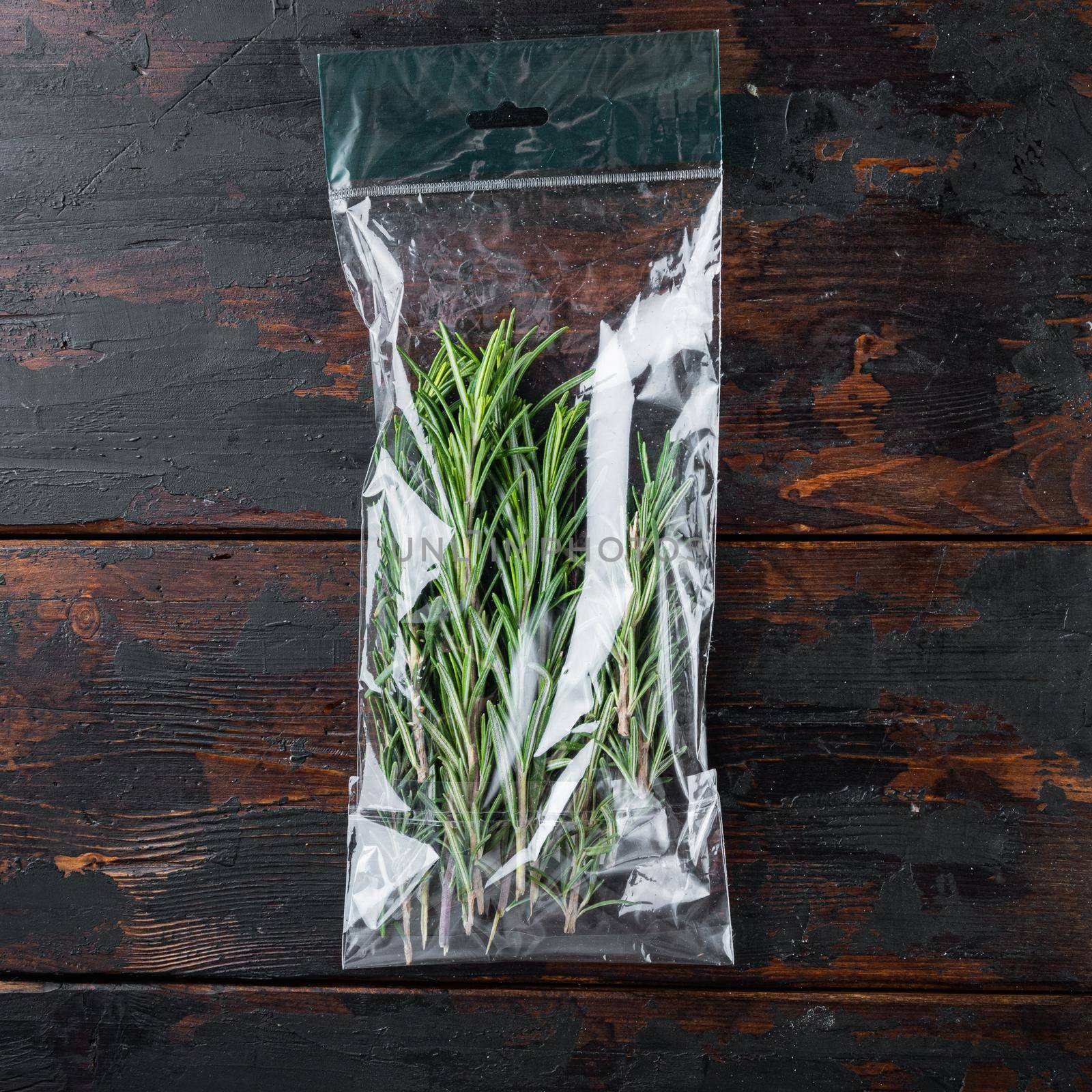 Rosemary in plastic bag, on dark wooden background, top view flat lay by Ilianesolenyi