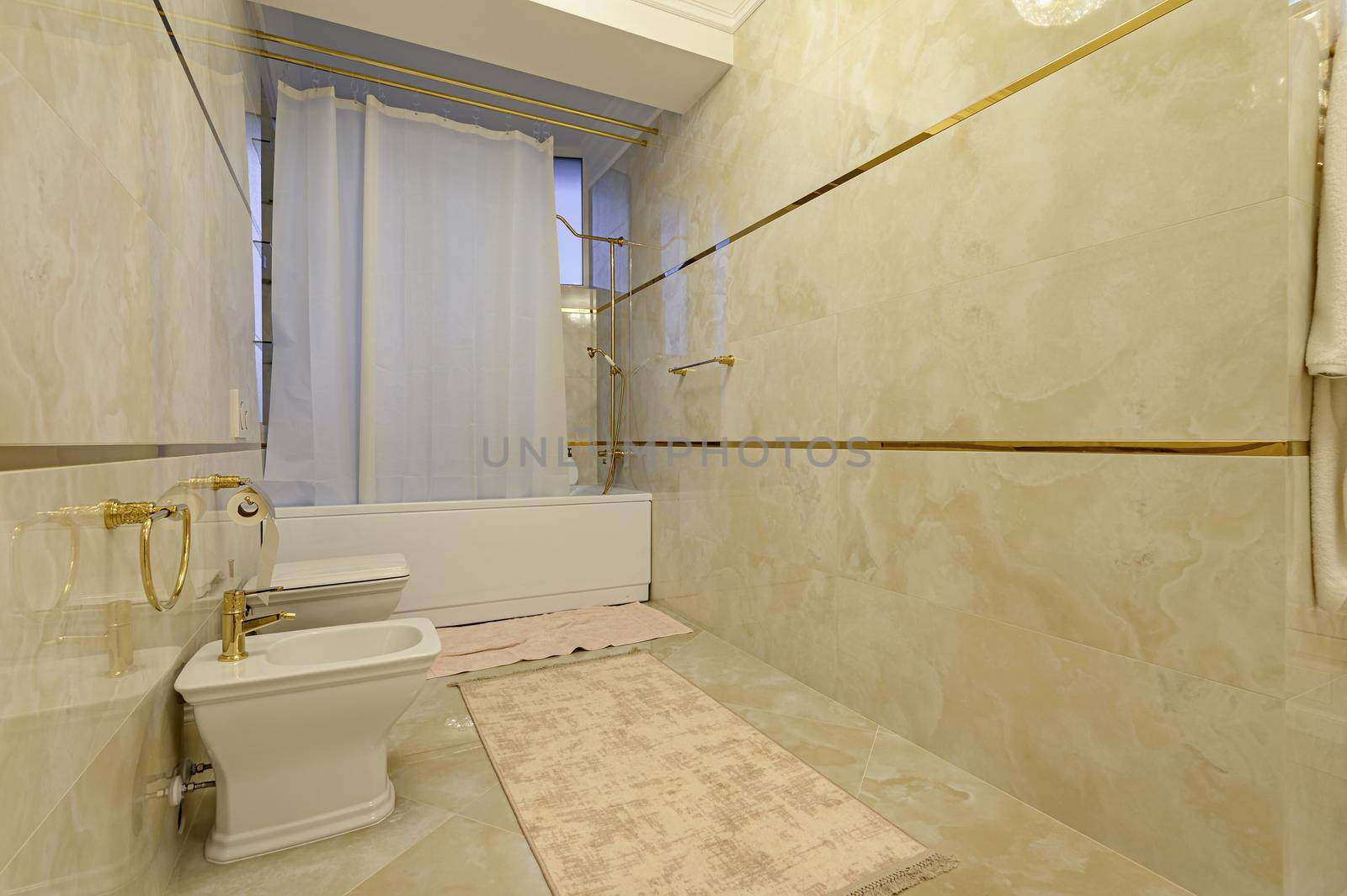 Modern luxury beige and golden bathroom with toilet, bidet and bathtub