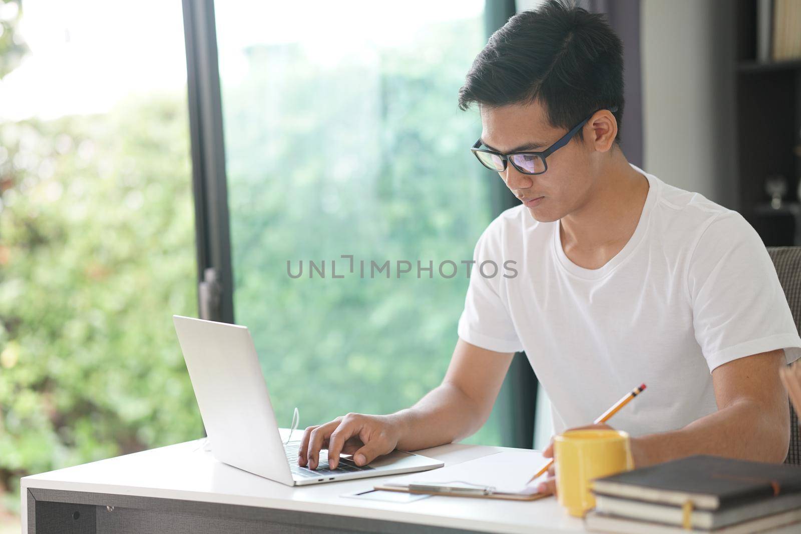 asian young teenage student man teenager entrepreneur working with computer studying learning online at home. e-learning webinar meeting. social distance in covid pandemic