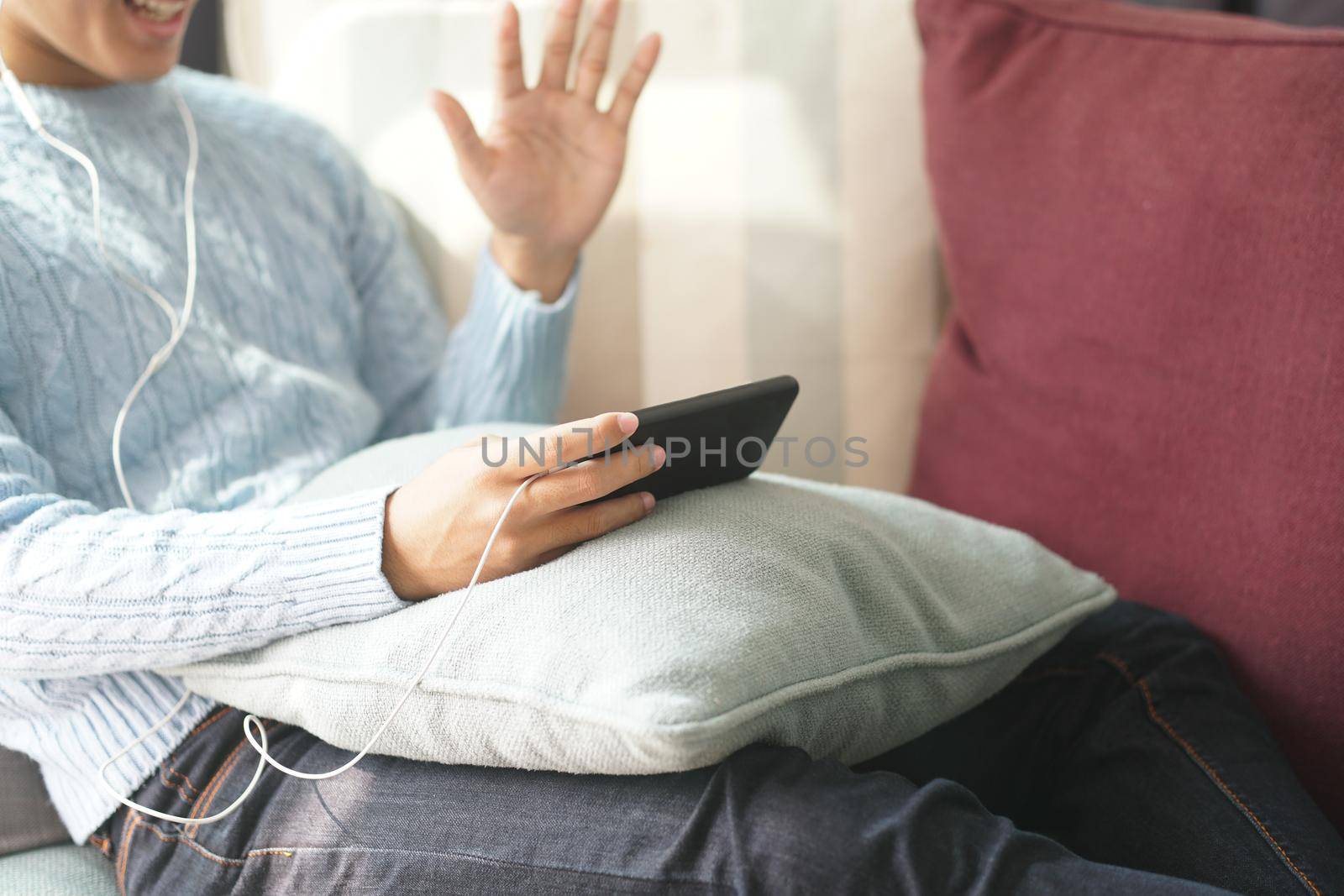 young asian man wearing earphones talking on video call meeting using smart mobile phone