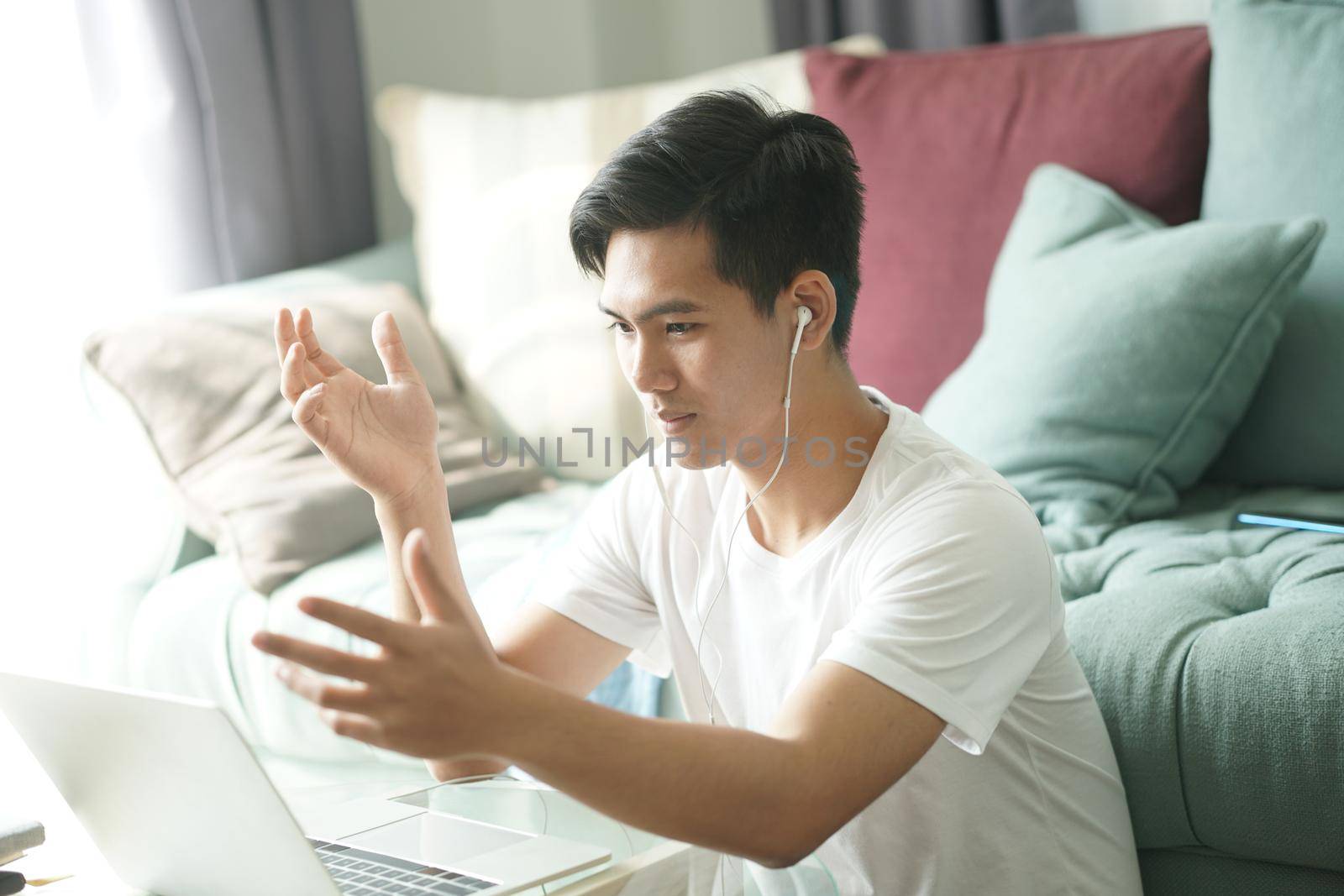 asian young teenage student man entrepreneur wear earphones working by video call conference studying learning online at home. e-learning webinar meeting. social distance in covid pandemic