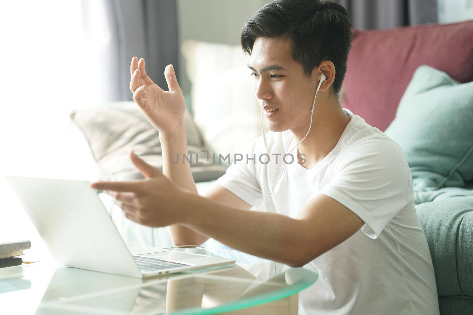 asian young teenage student man entrepreneur wear earphones working by video call conference studying learning online at home. e-learning webinar meeting. social distance in covid pandemic