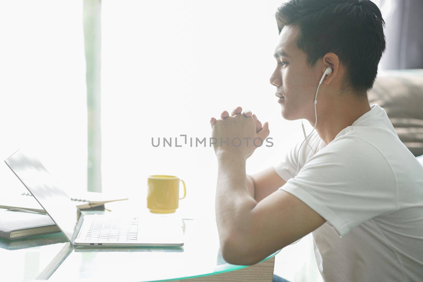 asian young student man teenager entrepreneur wear earphones working with computer studying learning online at home. e-learning webinar meeting. social distance in covid pandemic