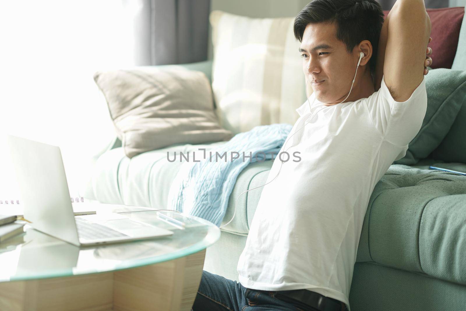 asian young student man teenager entrepreneur wear earphones stretching feeling tired bored sleepy while working with computer studying learning online at home. e-learning education