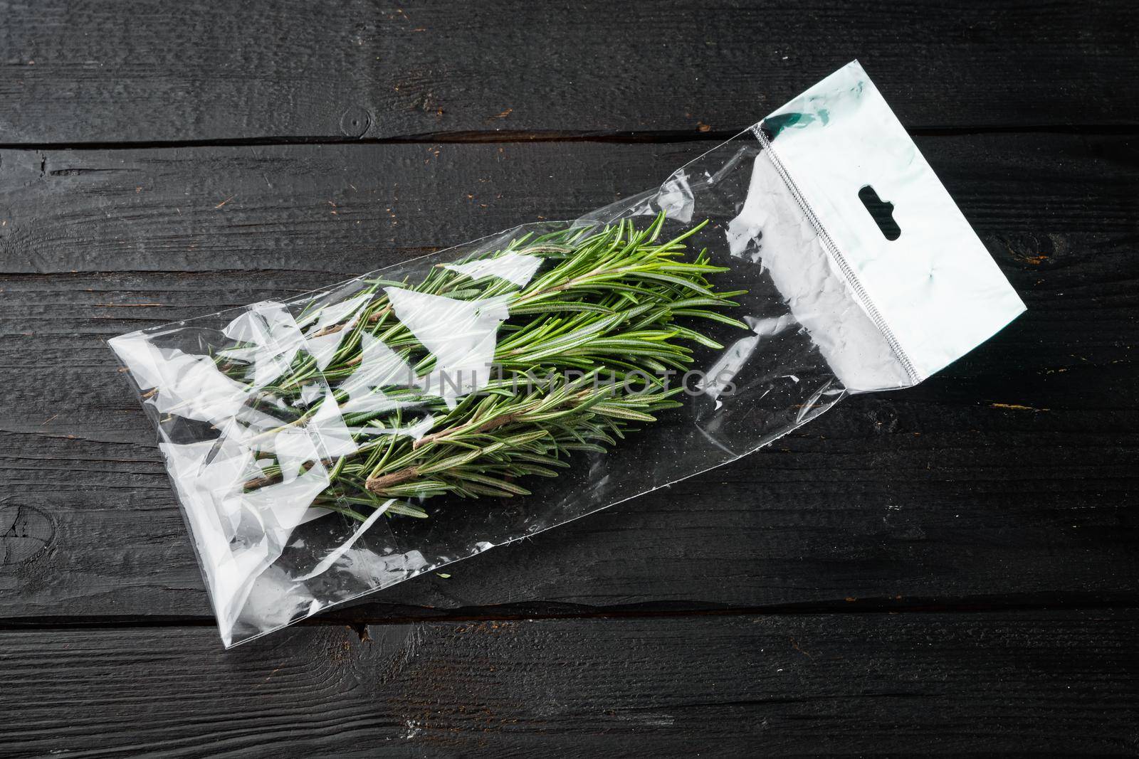 Rosemary in plastic bag, on black wooden table background by Ilianesolenyi