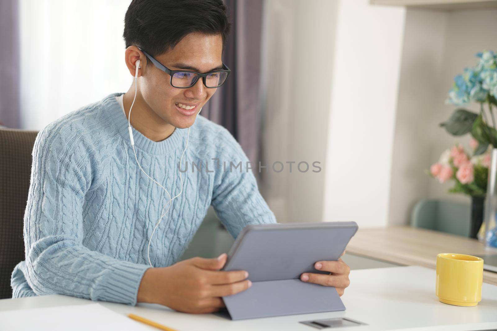 asian young teenage student man entrepreneur wear earphones working by video call conference studying learning online at home. e-learning webinar meeting. social distance in covid pandemic