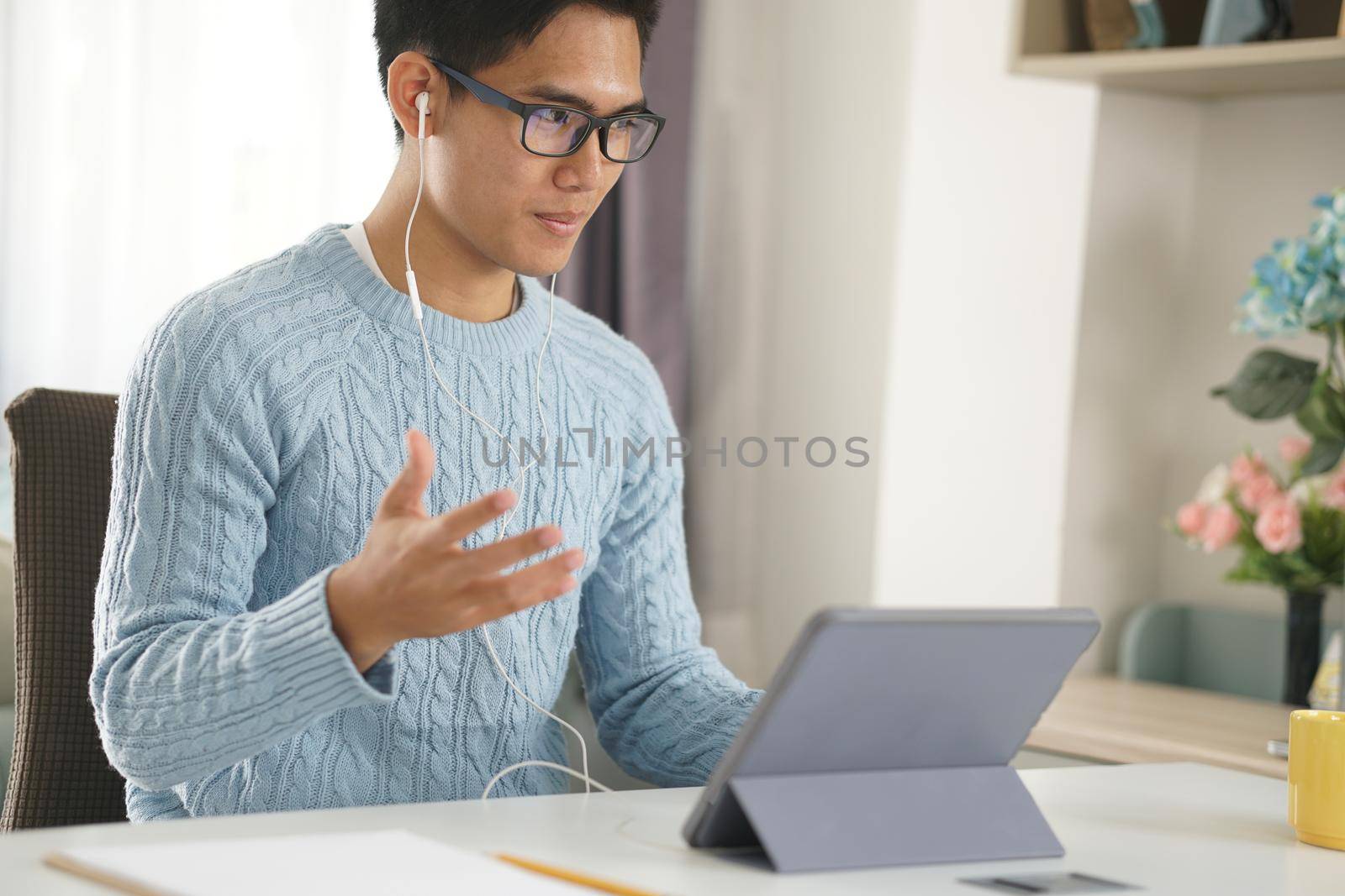 asian young teenage student man entrepreneur wear earphones working by video call conference studying learning online at home. e-learning webinar meeting. social distance in covid pandemic