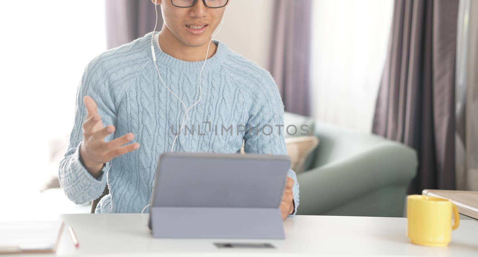 asian young teenage student man entrepreneur wear earphones working by video call conference studying learning online at home. e-learning webinar meeting. social distance in covid pandemic