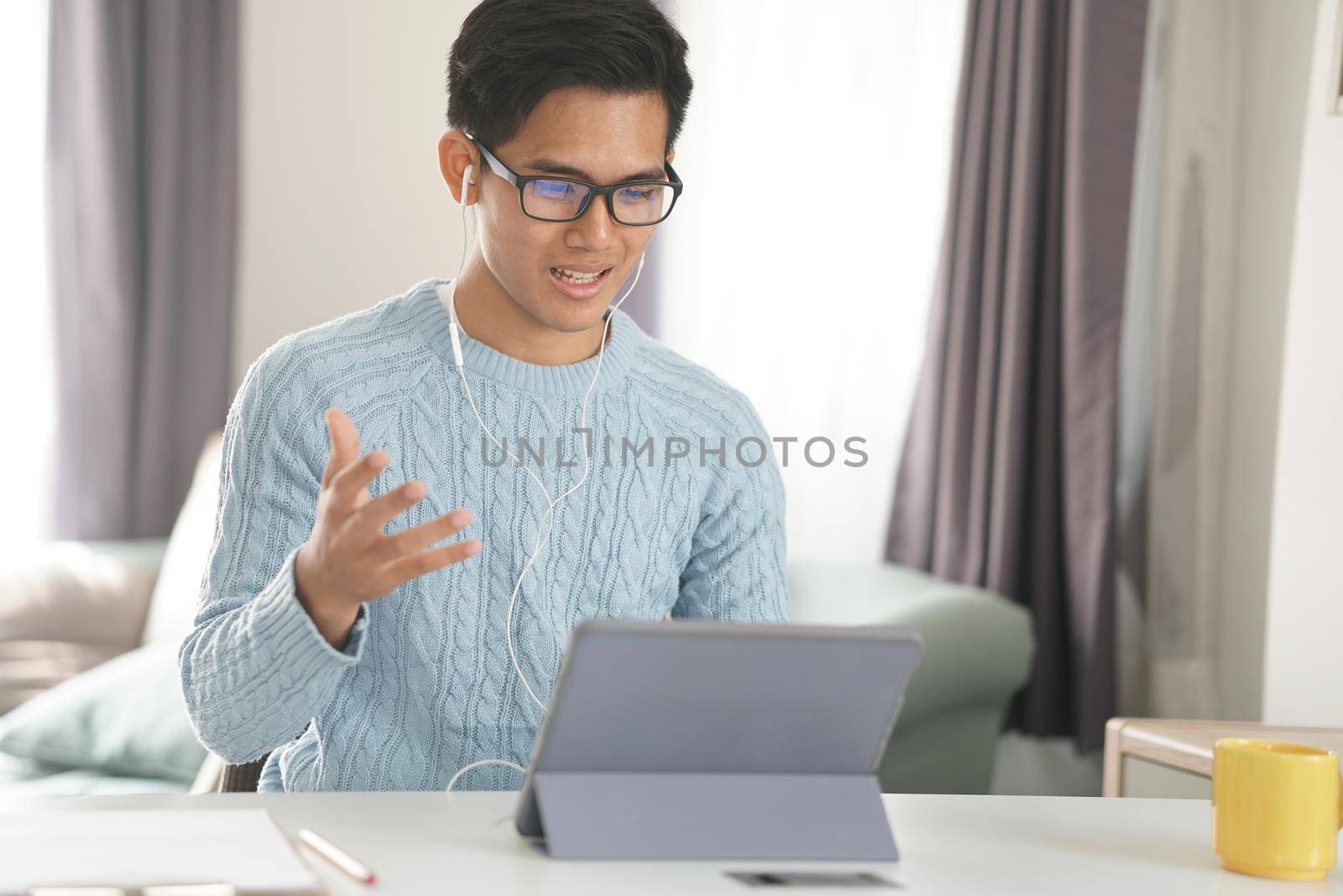 asian young teenage student man entrepreneur wear earphones working by video call conference studying learning online at home. e-learning webinar meeting. social distance in covid pandemic