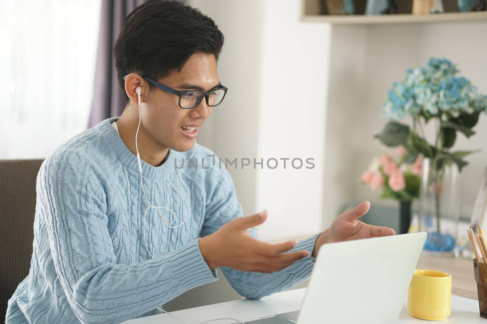 asian young teenage student man entrepreneur wear earphones working by video call conference studying learning online at home. e-learning webinar meeting. social distance in covid pandemic