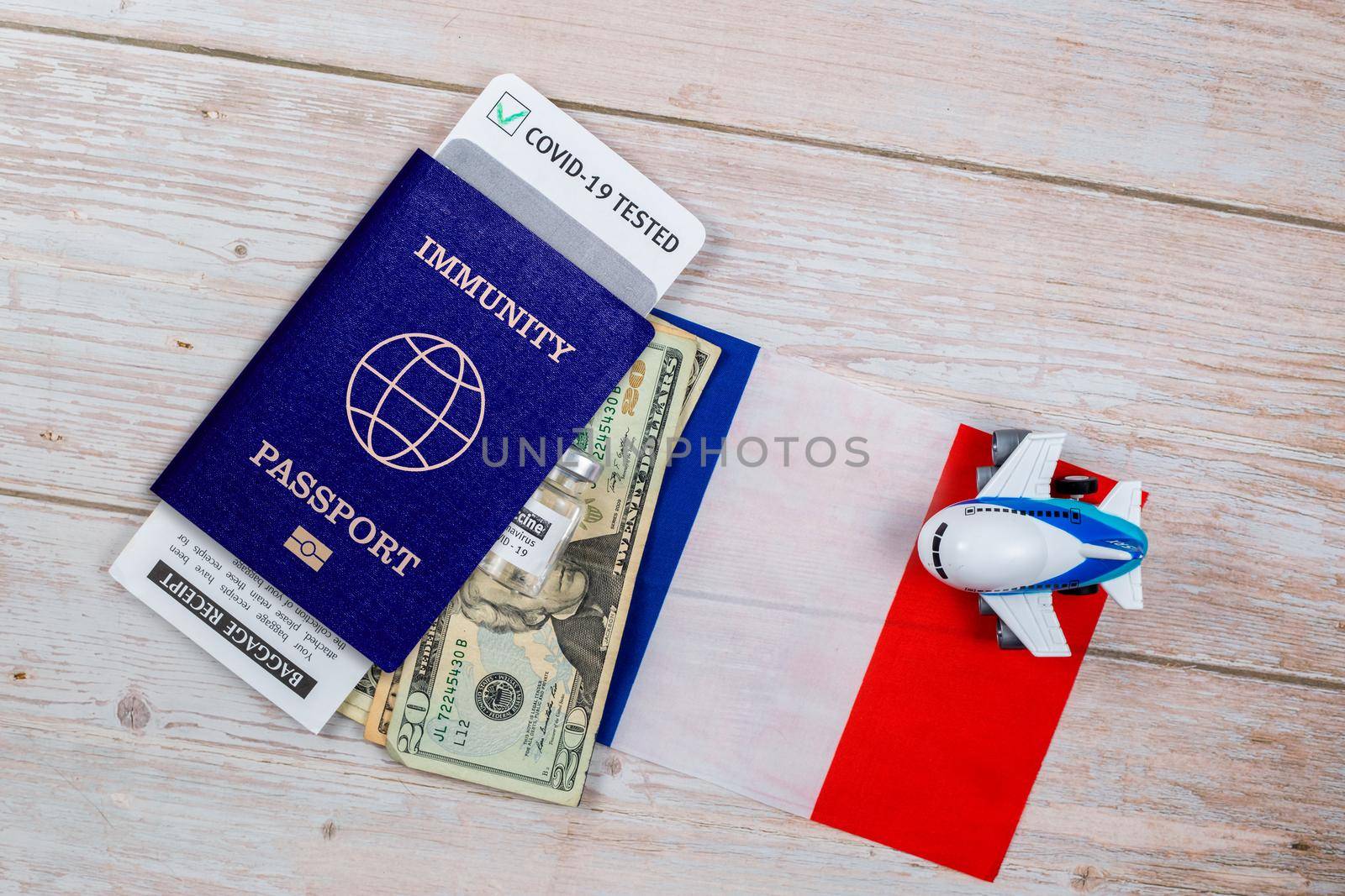 Concept of Immunity passport, certificate for traveling after pandemic for people who have had coronavirus or made vaccine. Passport with note COVID-19, banknotes, vaccine bottle on flag of France