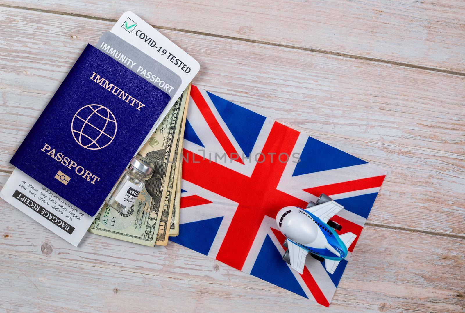 Concept of Immunity passport, certificate for traveling after pandemic for people who have had coronavirus or made vaccine. Passport with note COVID-19,money, vaccine bottle on flag of Great Britain