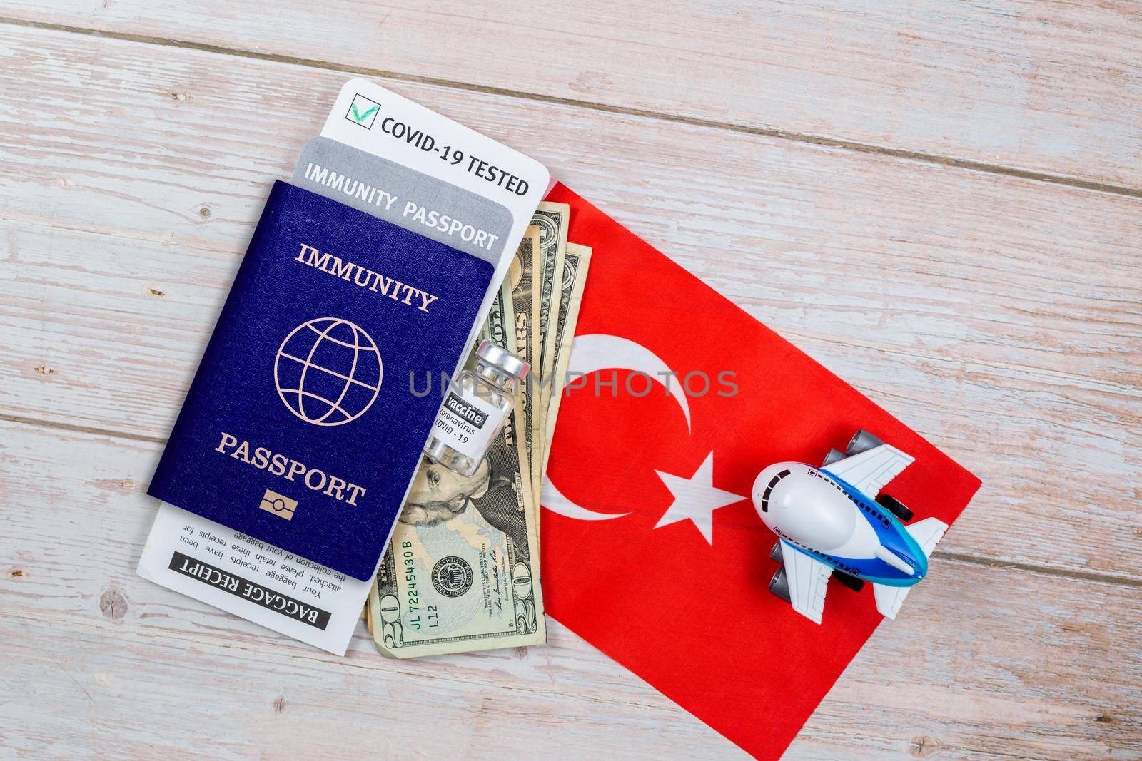Concept of Immunity passport, certificate for traveling after pandemic for people who have had coronavirus or made vaccine. Passport with note COVID-19, banknotes, vaccine bottle on flag of Turkey