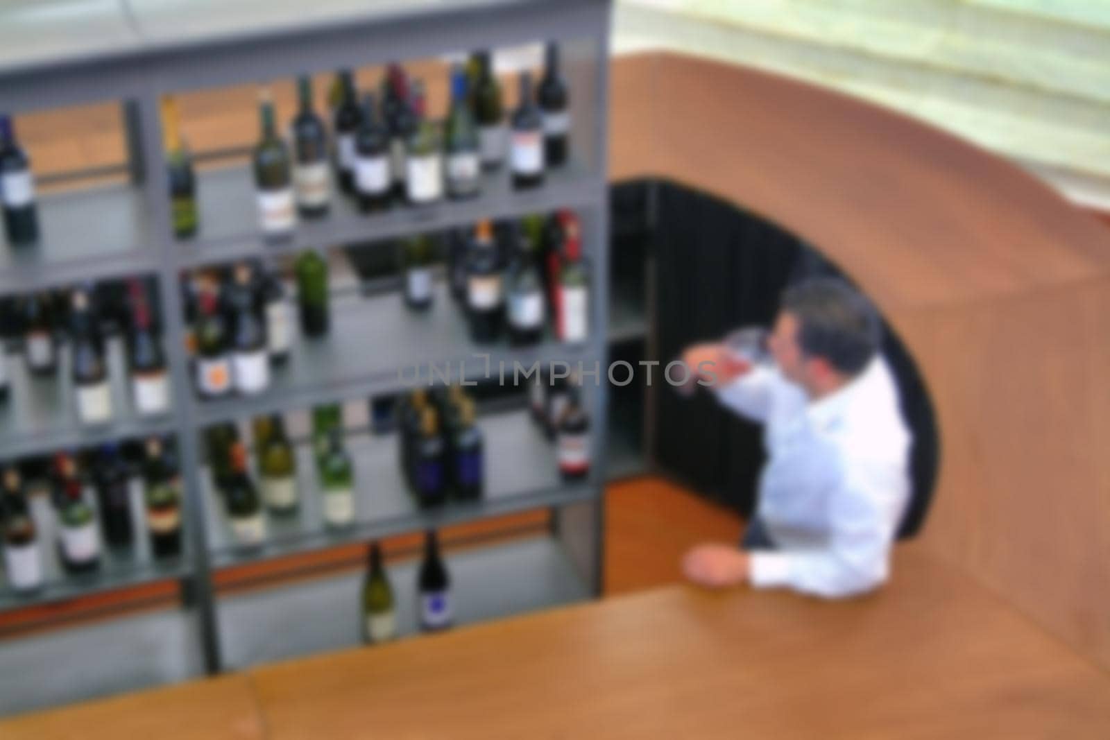 Wine tasting man above view with bottle shelves and counter blur effect