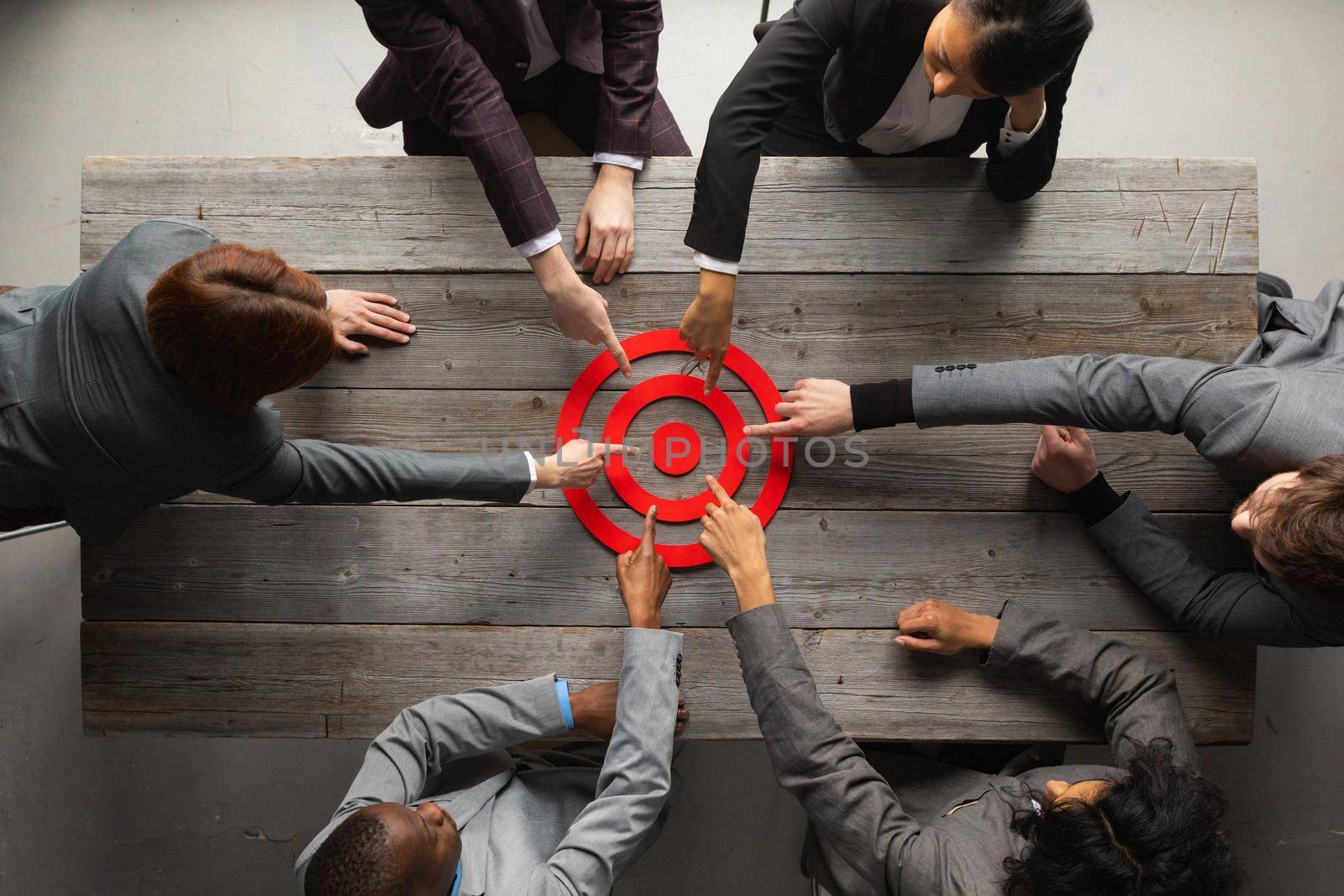 Team of business people pointing at red target at meeting table