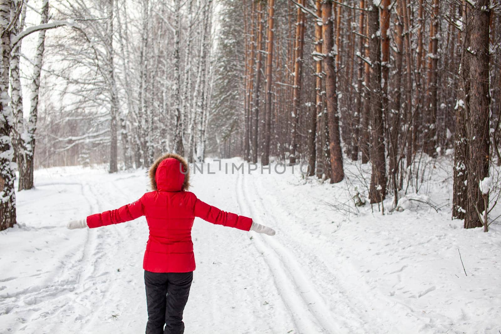 A girl in a red jacket walks through a snow-covered forest by AnatoliiFoto